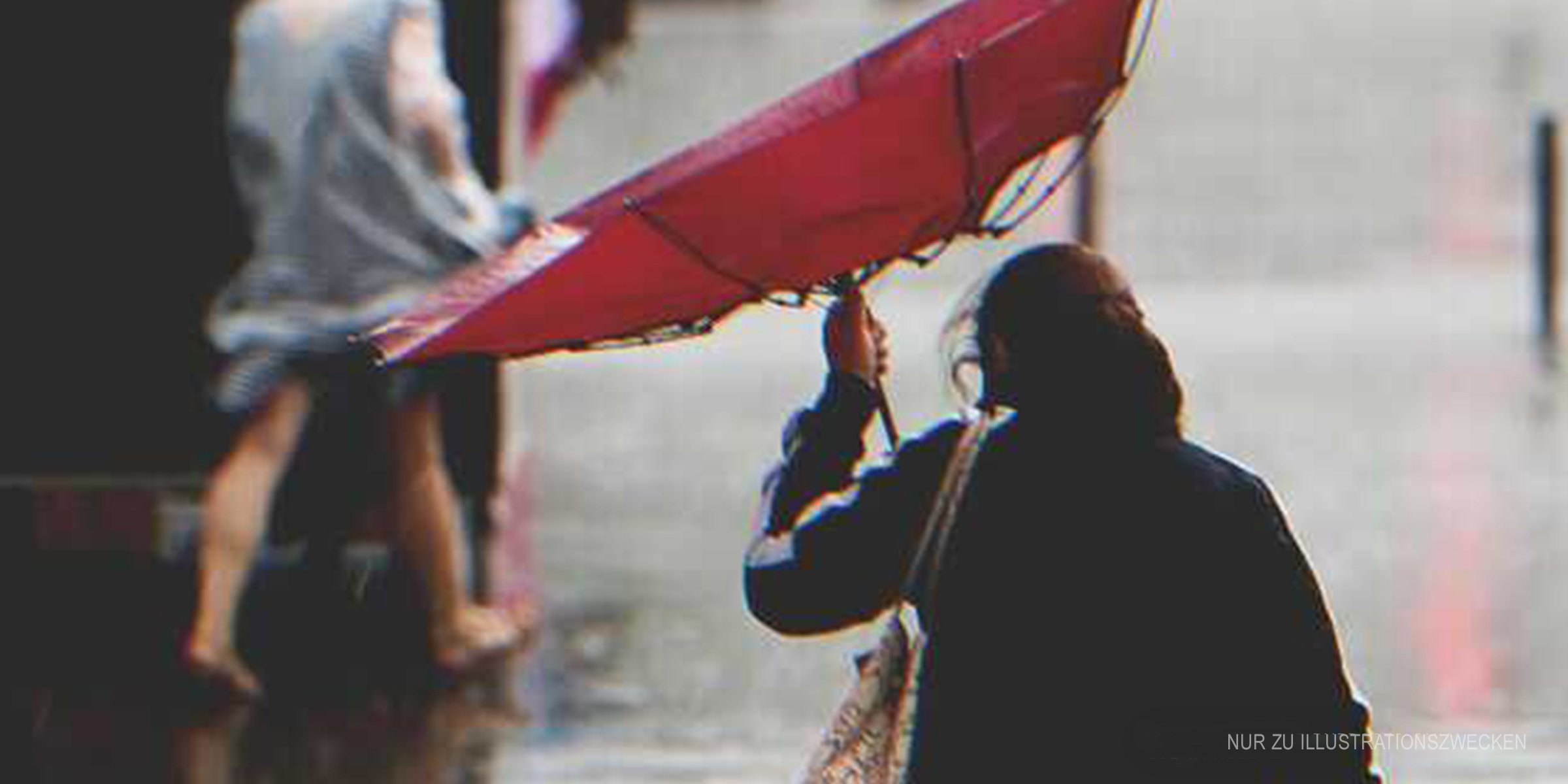 Frau mit kaputtem Regenschirm im Regen | Quelle: Shutterstock