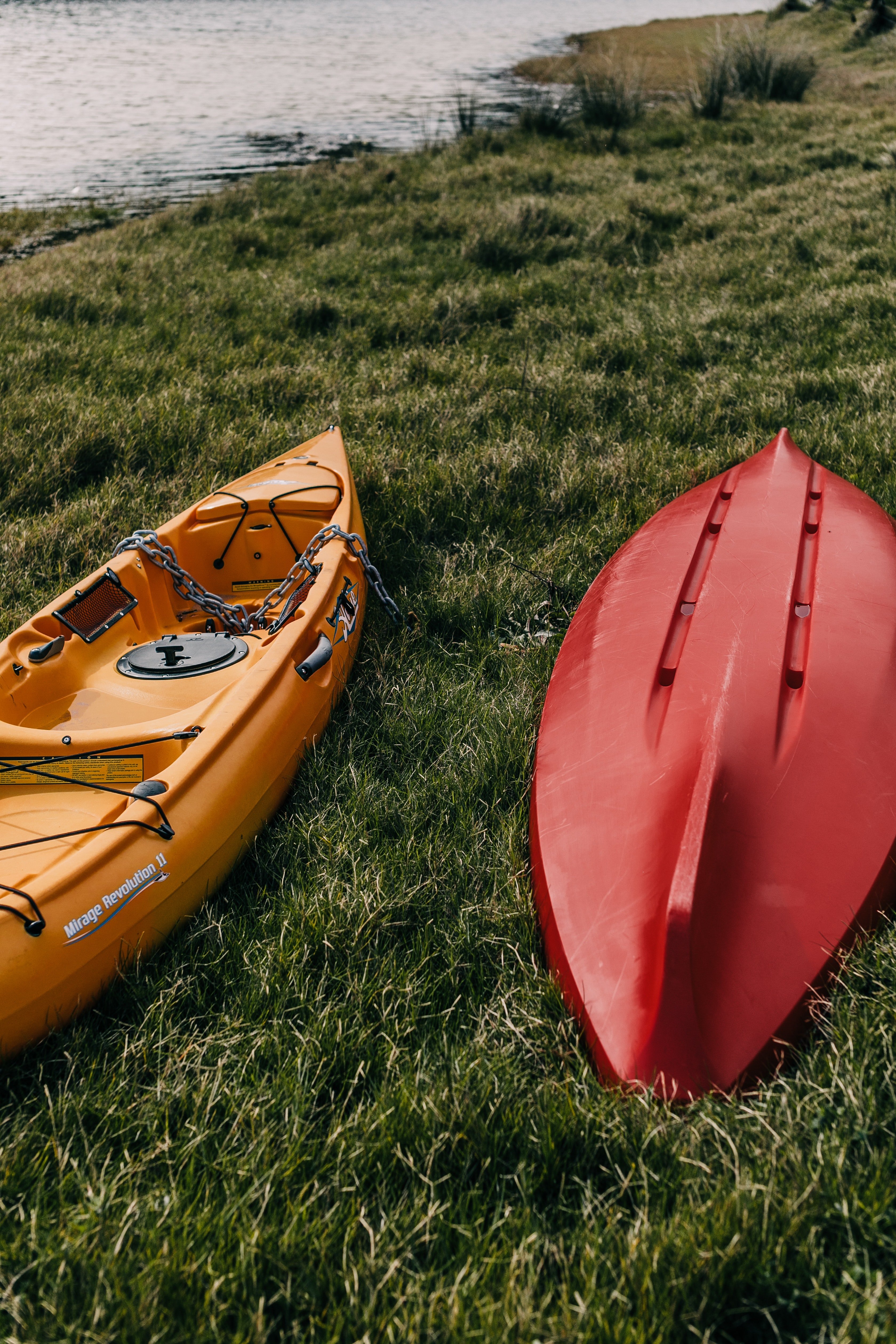 A red and yellow canoe lying on the grass. | Photo: pexels