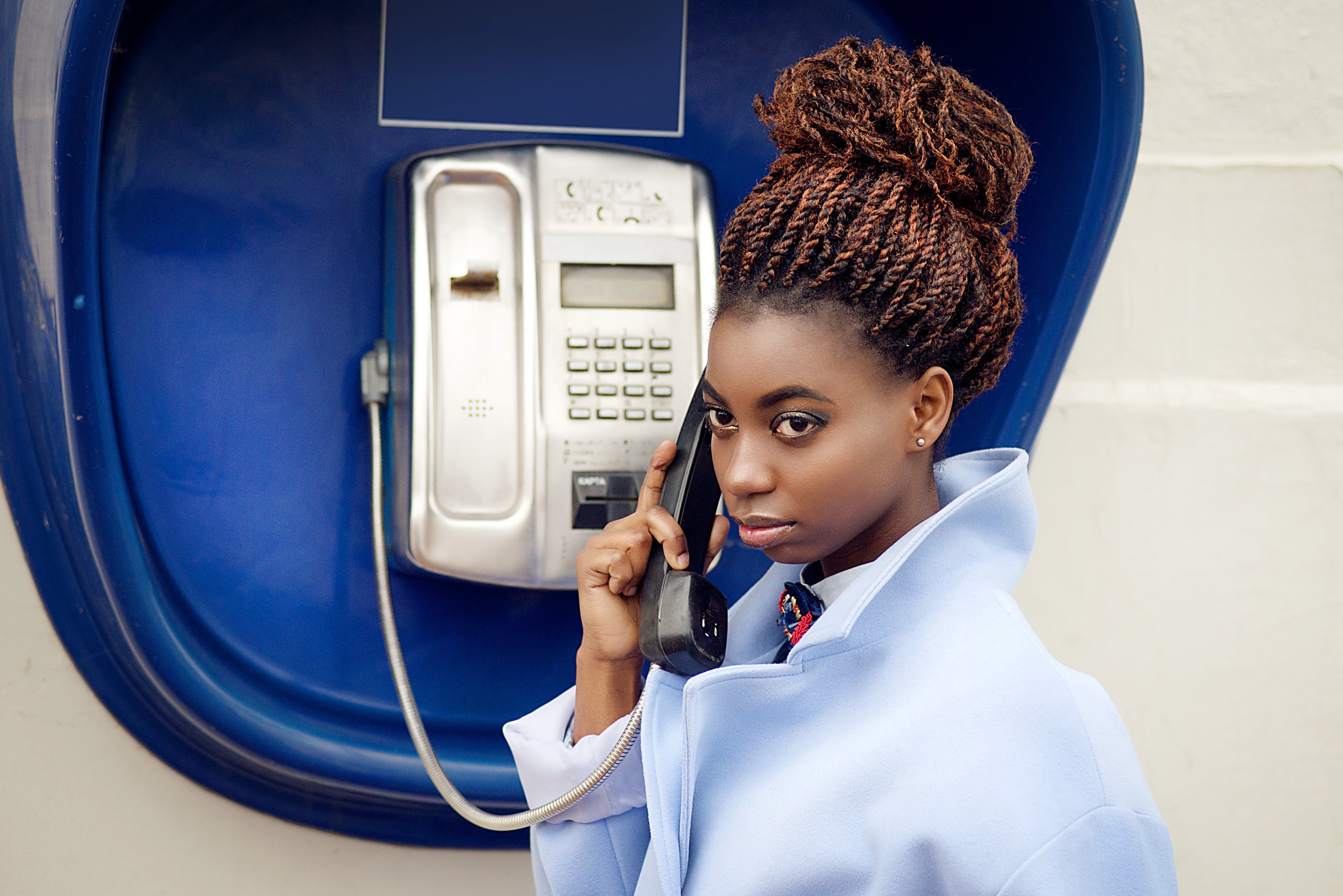 Une jeune fille utilise un téléphone public | Photo : Shutterstock