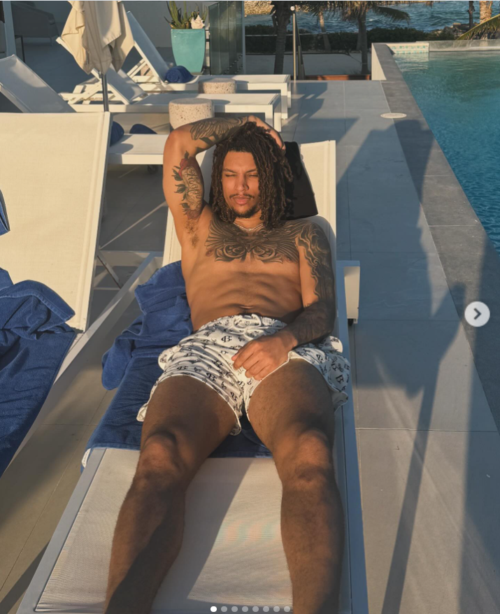 Brandon Clarke relaxes on a poolside lounge chair during a tropical getaway, showing off his tattoos while soaking up the sun beside the water. | Source: Instagram/brandon_clarke23
