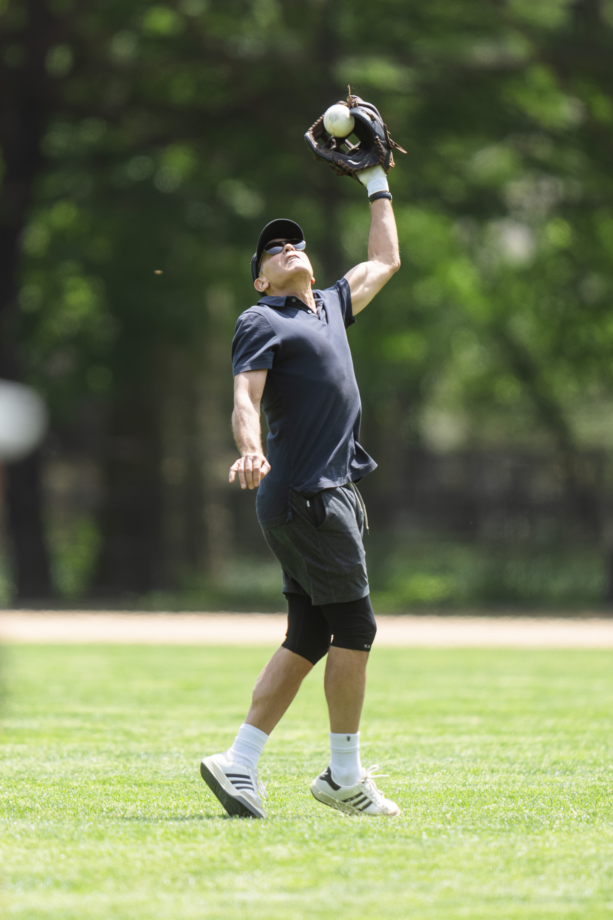 Clooney reaches high into the air, glove open just in time to make the catch. Focused and alert, he tracks the ball right into his mitt.