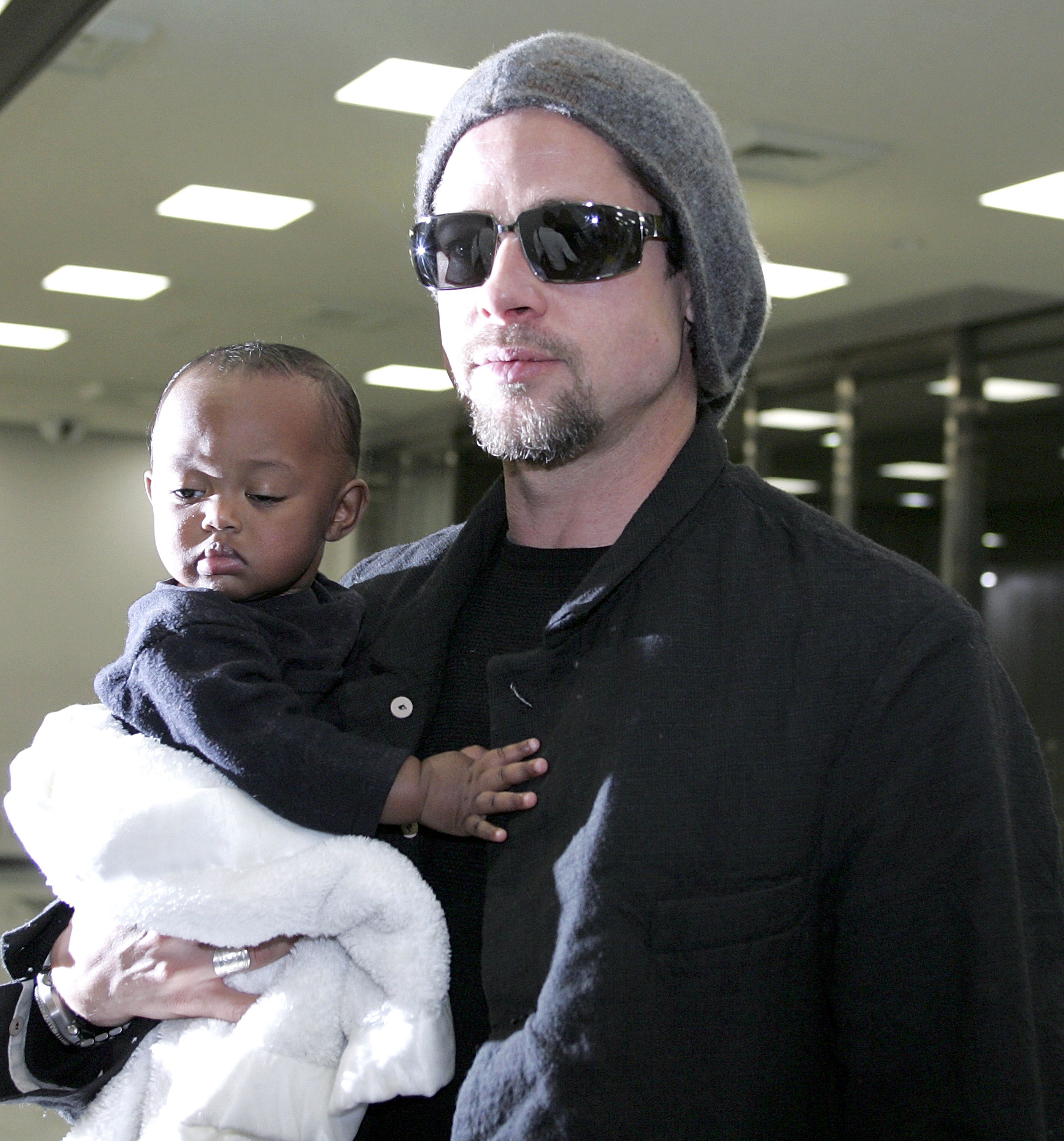 Brad Pitt L holds Zahara Marley Jolie as they arrive at the New Tokyo International Airport on November 27, 2005 in Narita, Japan. | Source: Getty Images
