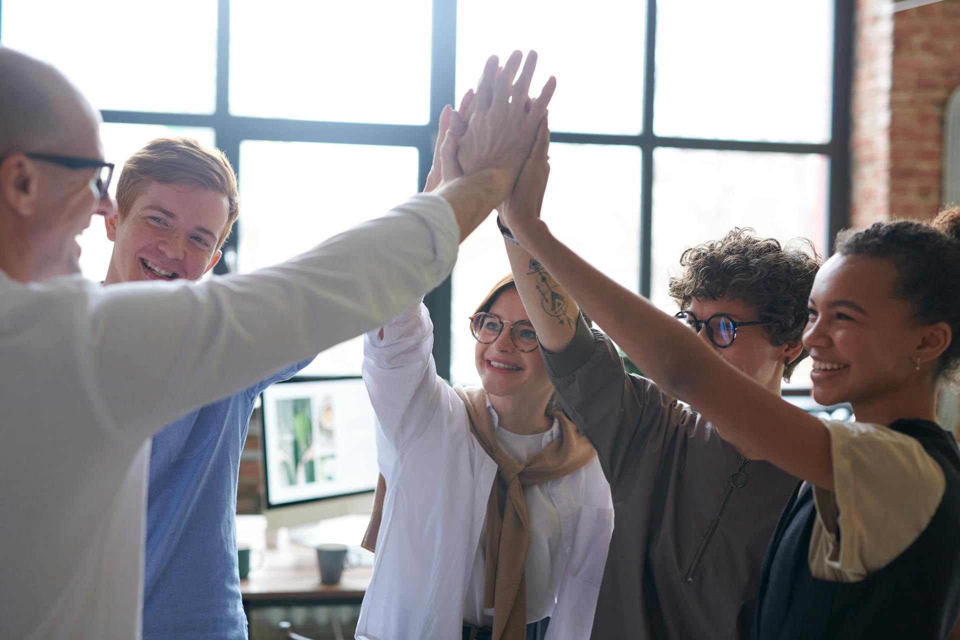 A photo showing employees doing a huddle with their boss | Source: Pexels