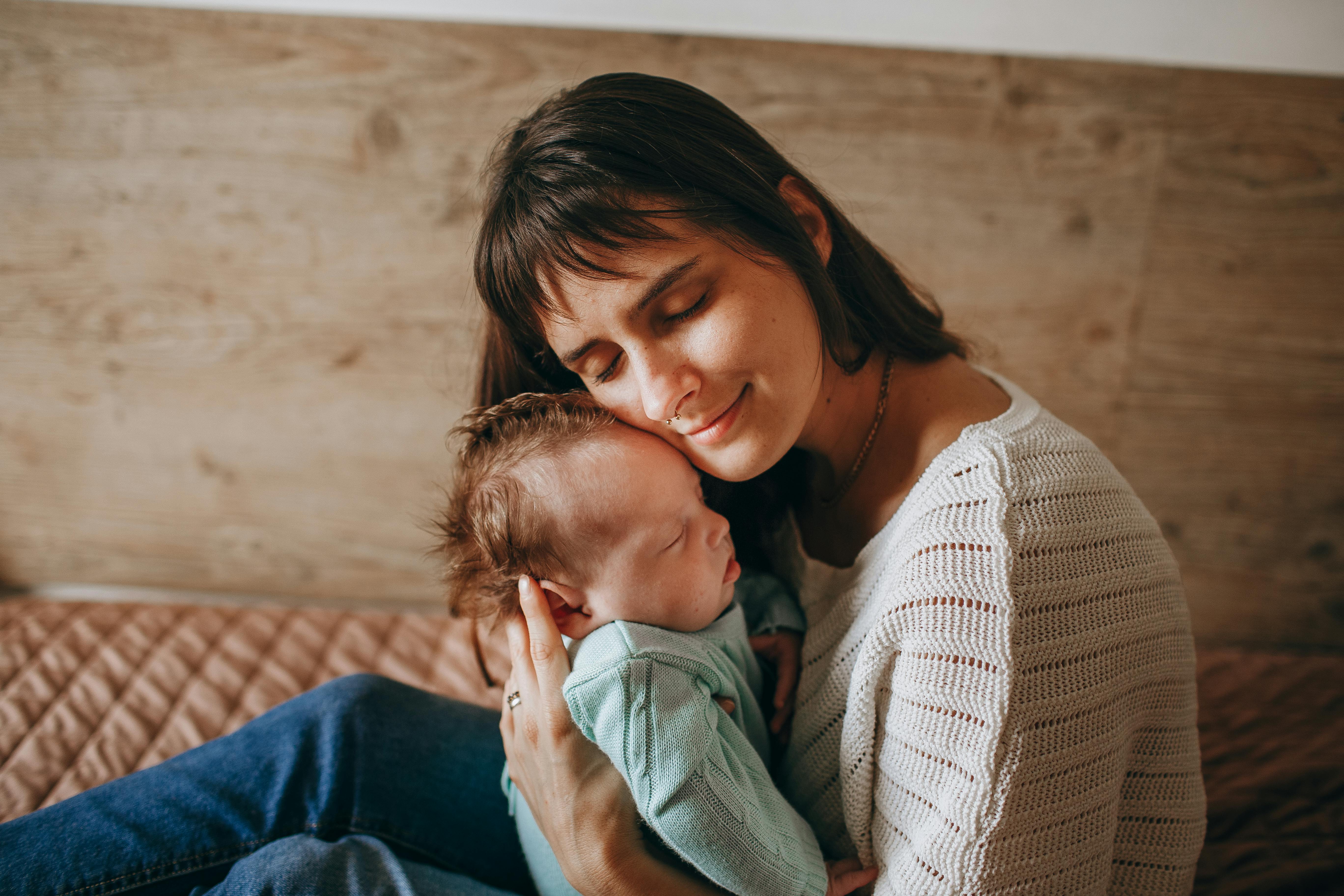 A woman smiling while cuddling a baby | Source: Pexels