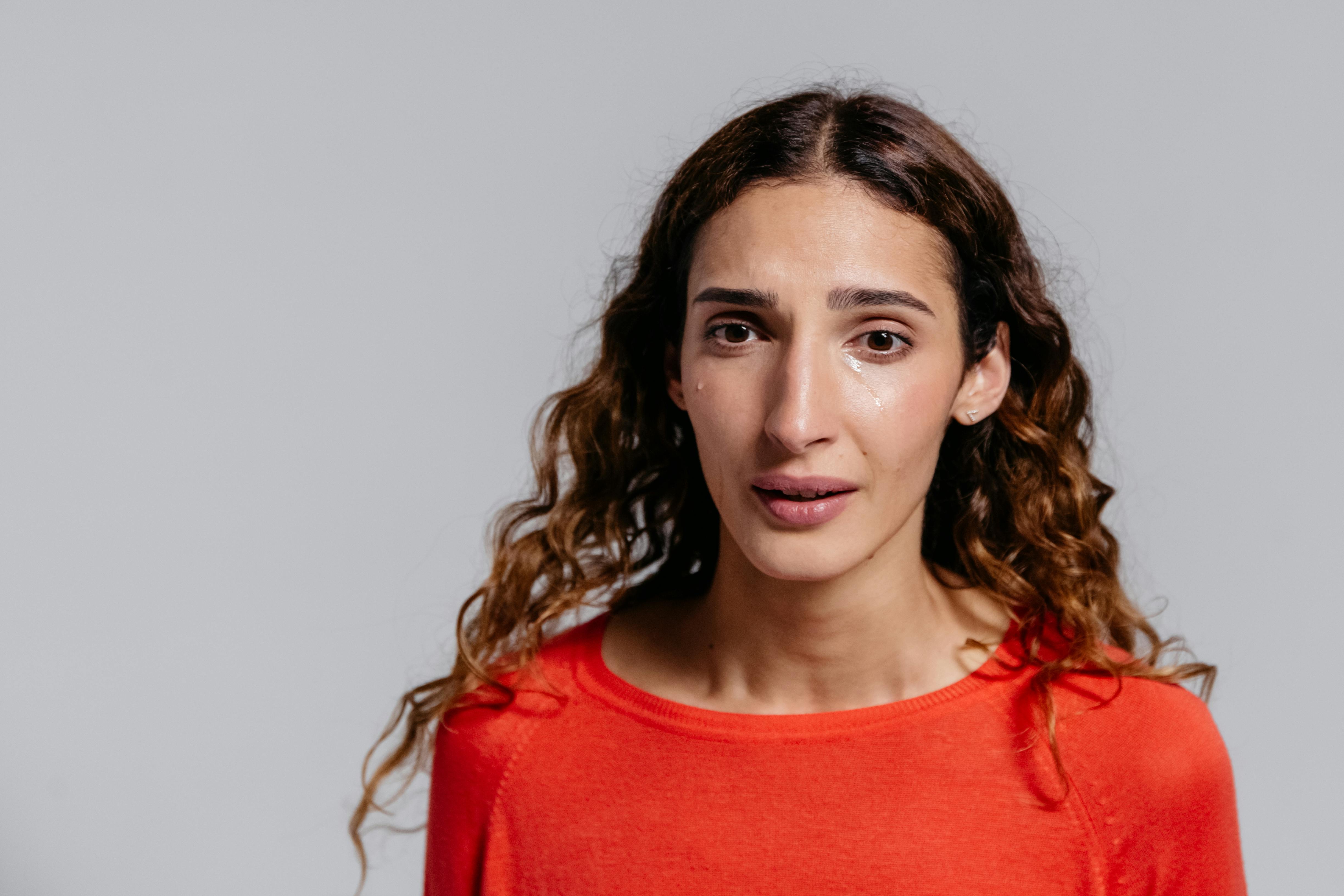 A crying woman in a red sweater | Source: Pexels