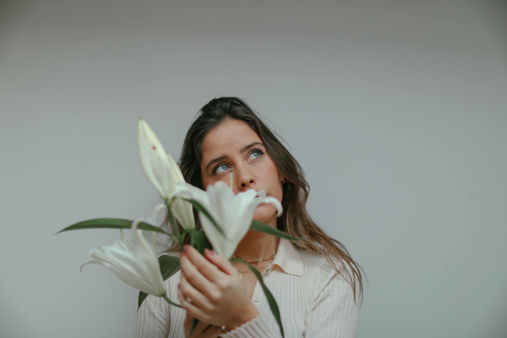 A woman lost in thought while holding white lilies | Source: Pexels