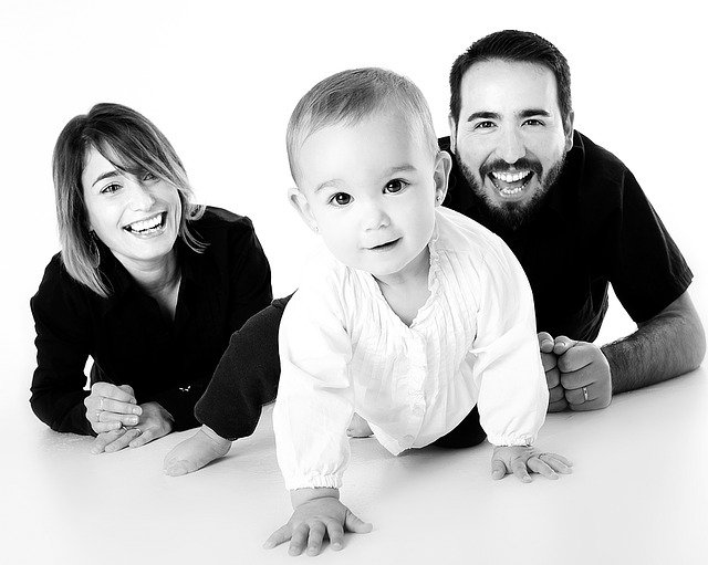 Bebé gateando con sus aparentes padres al fondo. | Foto: Pixabay
