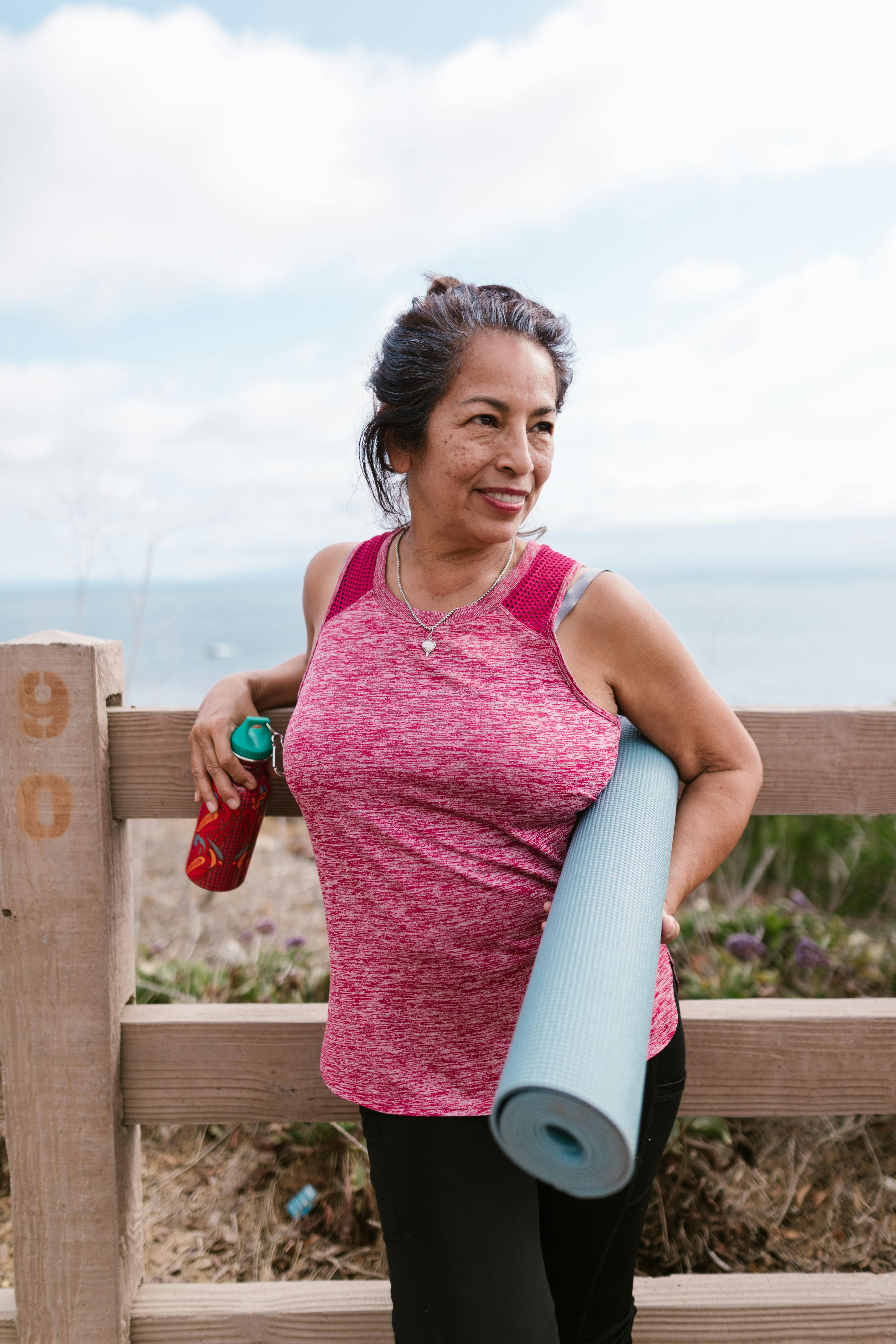 An older woman holding a water bottle and an exercise mat | Source: Pexels