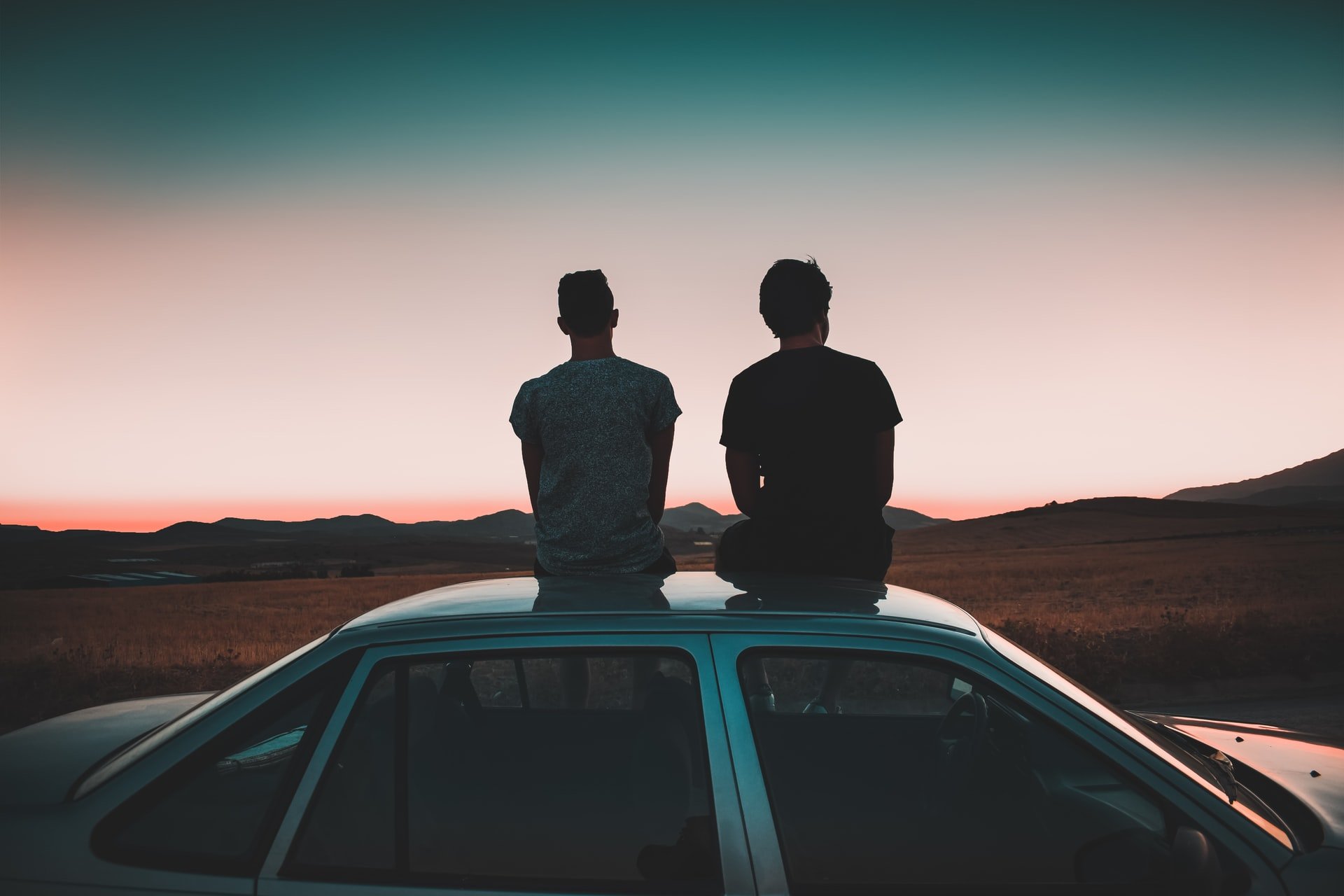 Two men sitting on the roof of their car | Source: Unsplash