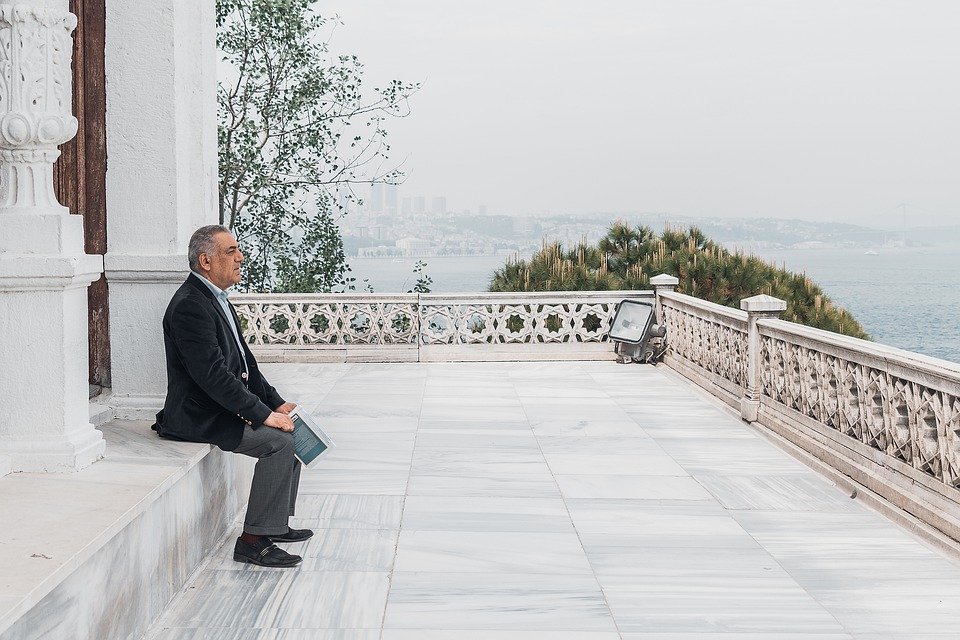 Hombre sentado en una terraza mirando hacia el horizonte. │Foto: Pixabay