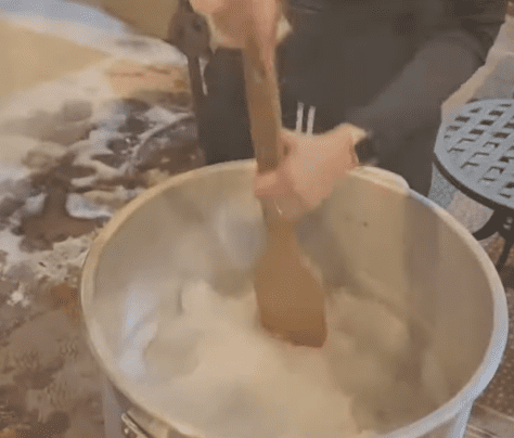 Photo of woman stirring snow with a wooden paddle | Photo: Youtube /  KATC