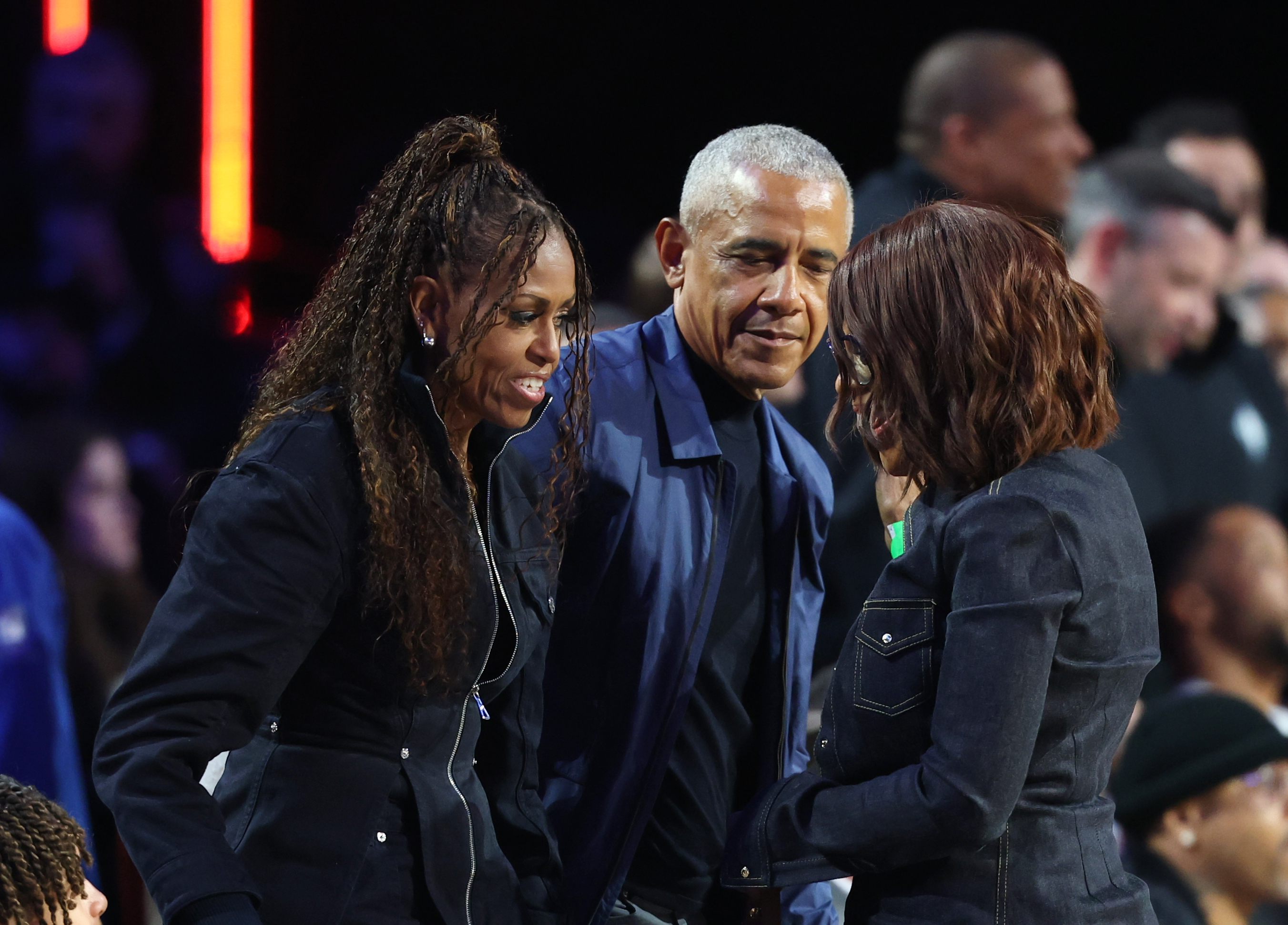 Michelle and Barack Obama interacting with another attendee at the sports event. | Source: Getty Images