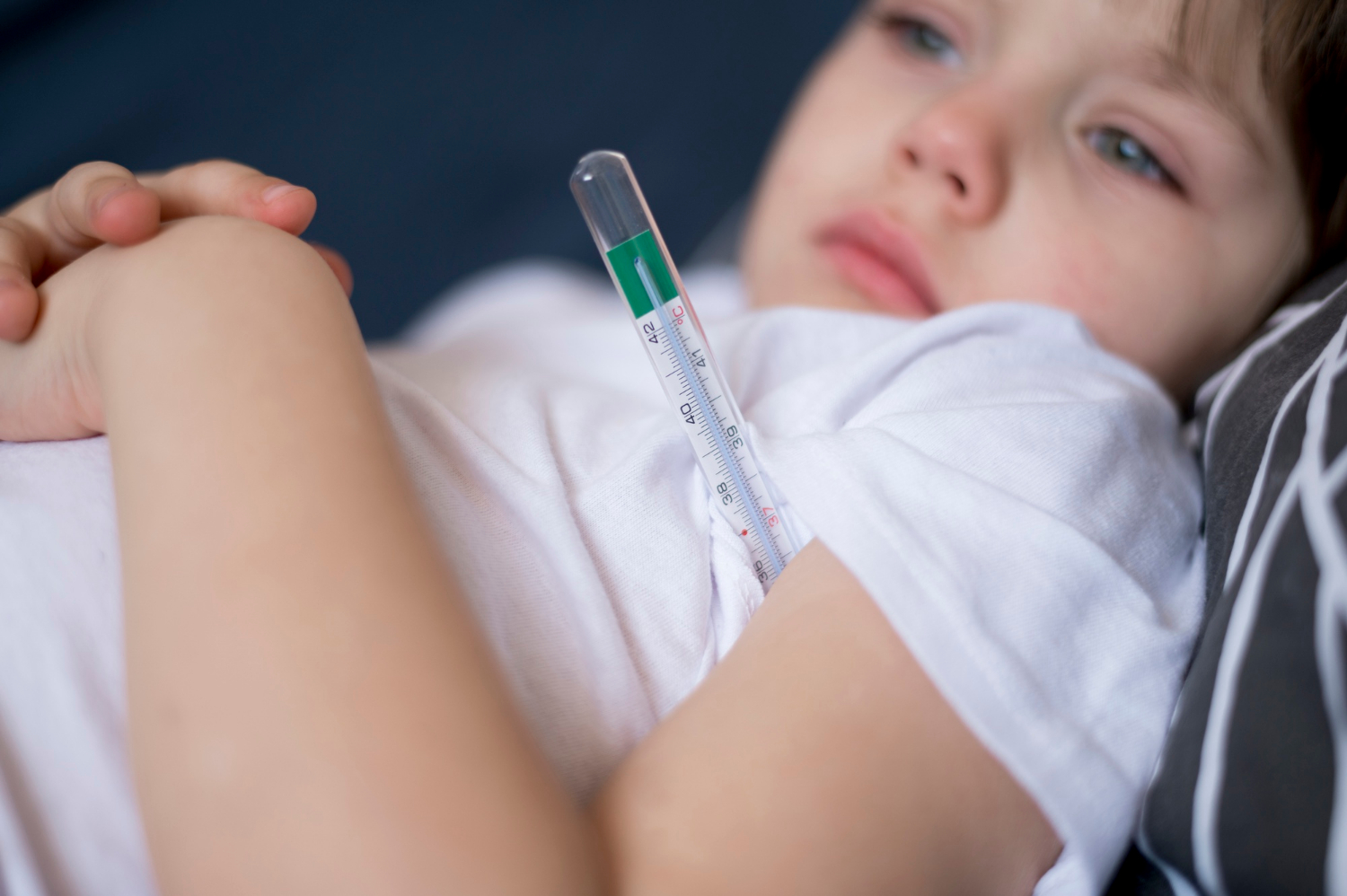 Close-up shot of a resting sick child with a thermometer | Source: Freepik