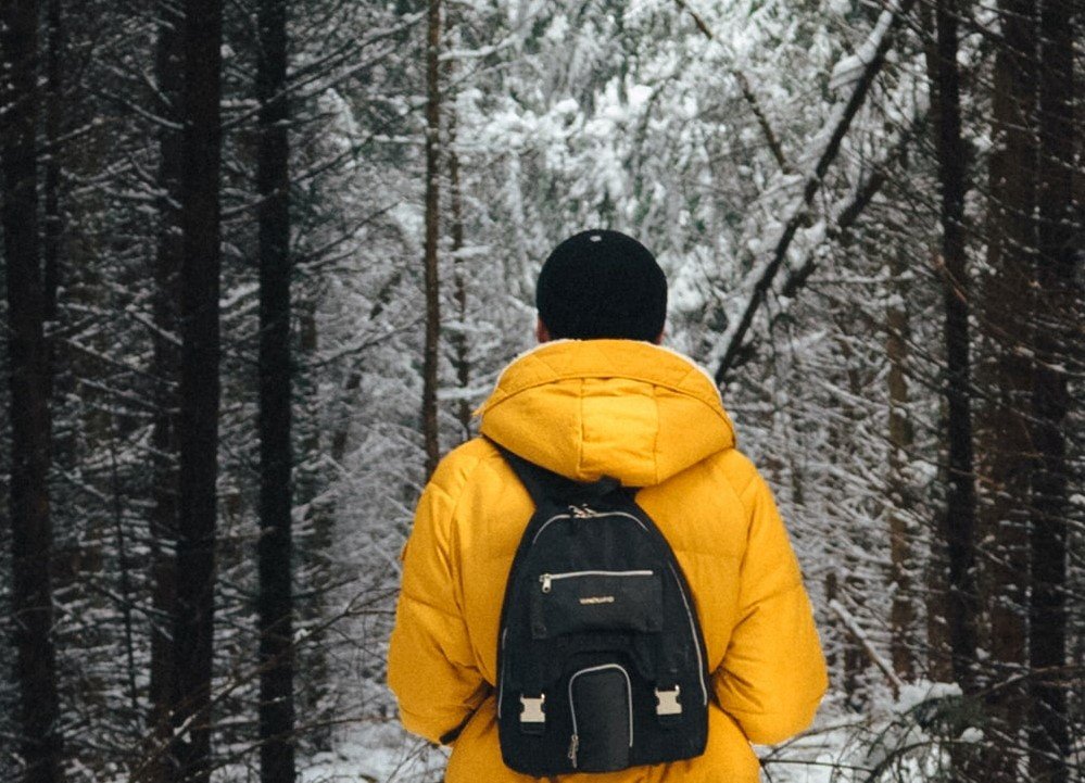 Un chico usando una sudadera con capucha mientras camina por el bosque. | Foto: Unsplash