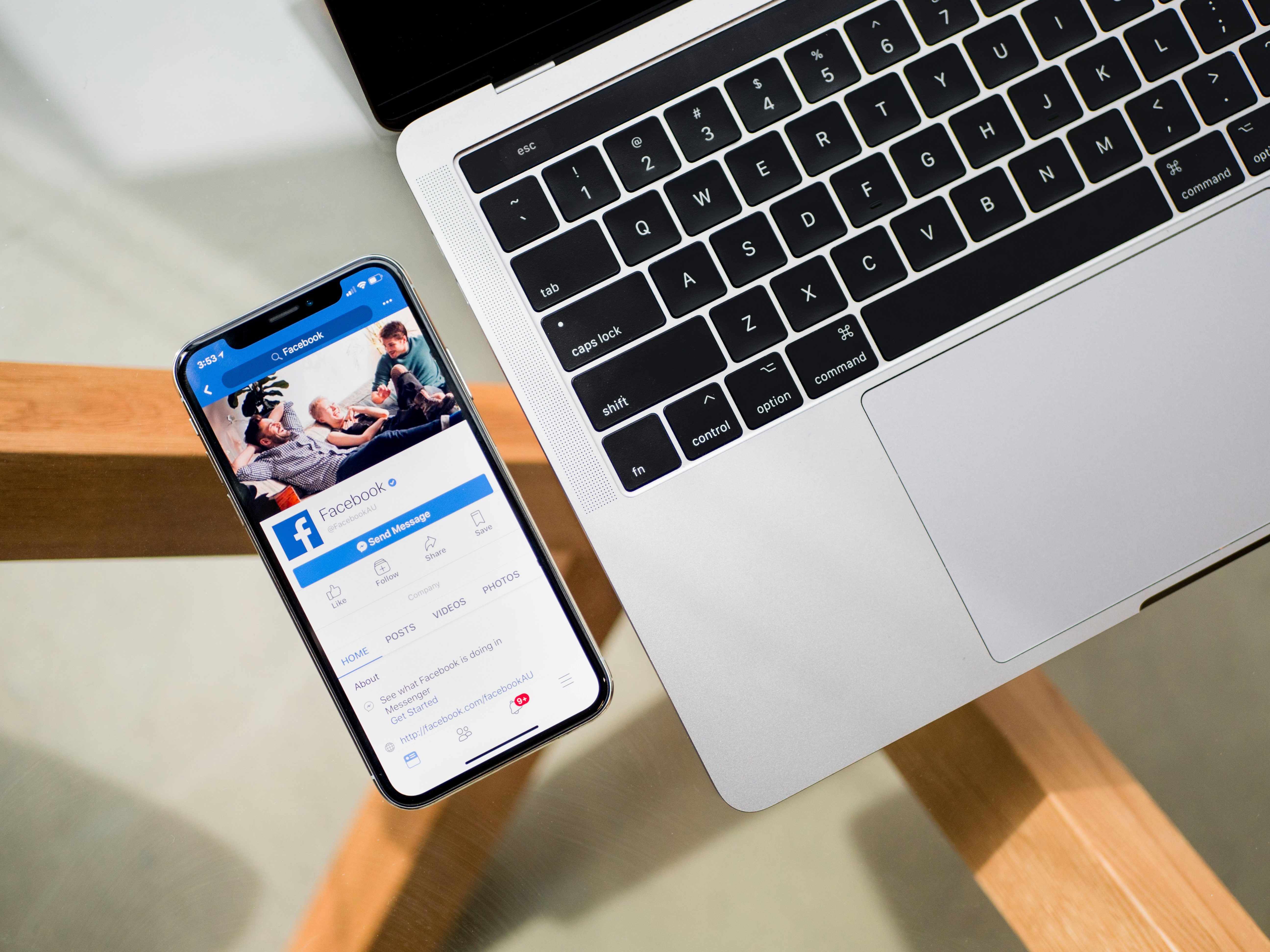 Facebook app open on a phone beside a laptop | Source: Unsplash