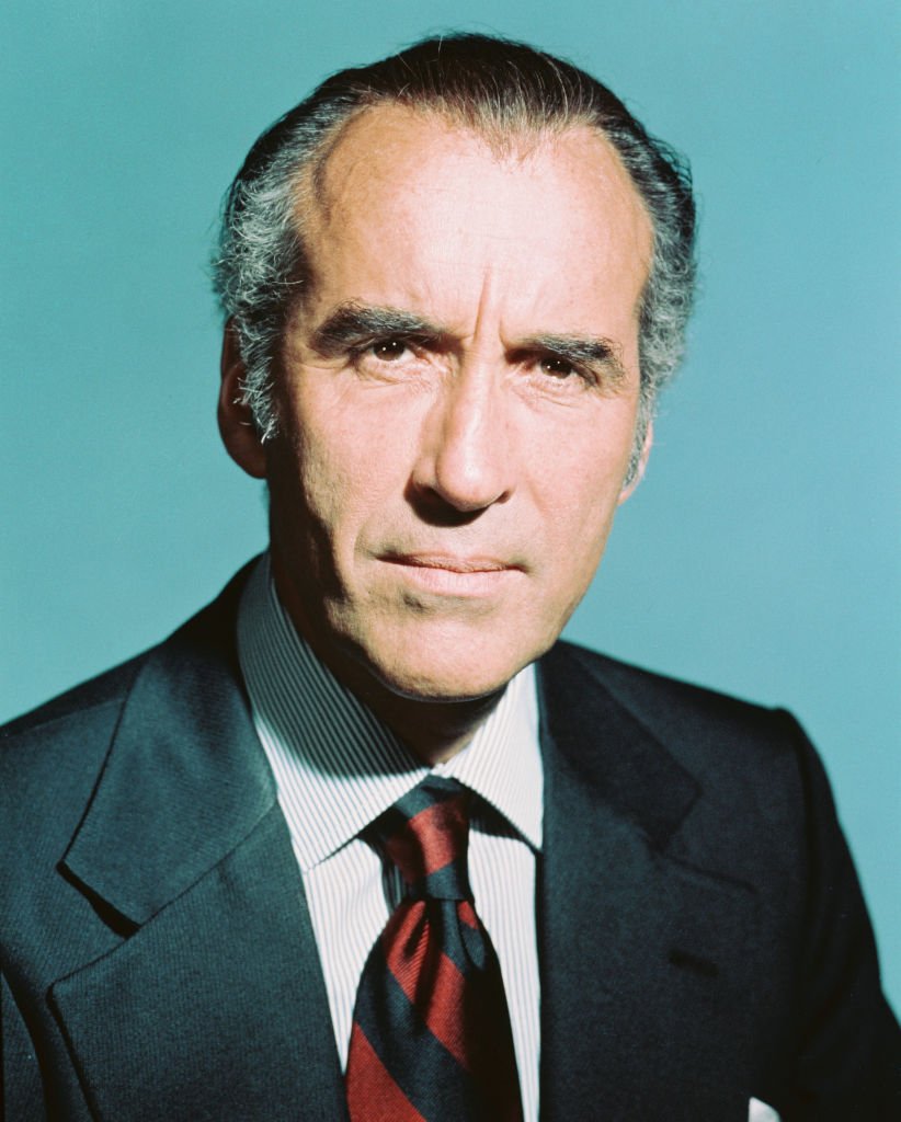 Late Christopher Lee, British actor, wearing a red-and-black striped tie, in a studio portrait, against a light blue background, circa 1970. | Photo: Getty Images