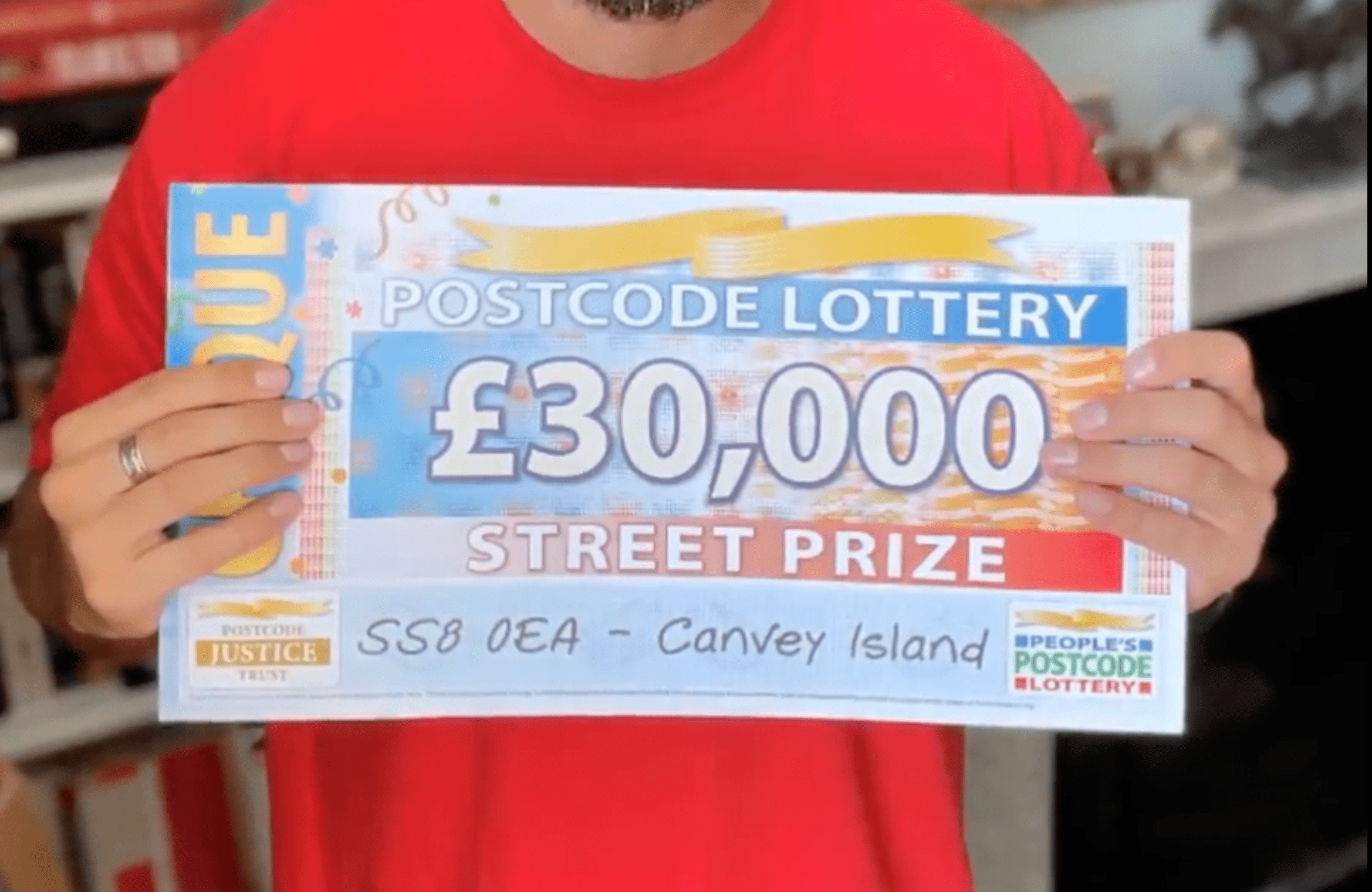 People’s Postcode Lottery ambassador holds up a cheque to show a woman that she has won £30,000 (about $41,300) in the lottery | Photo: Twitter/BBCEssex