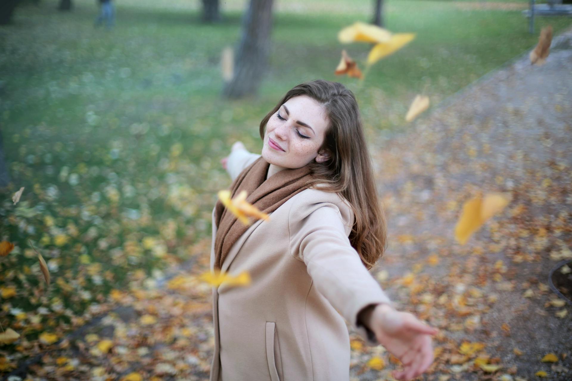 A young woman smiling with her eyes closed and her arms wide open | Source: Pexels