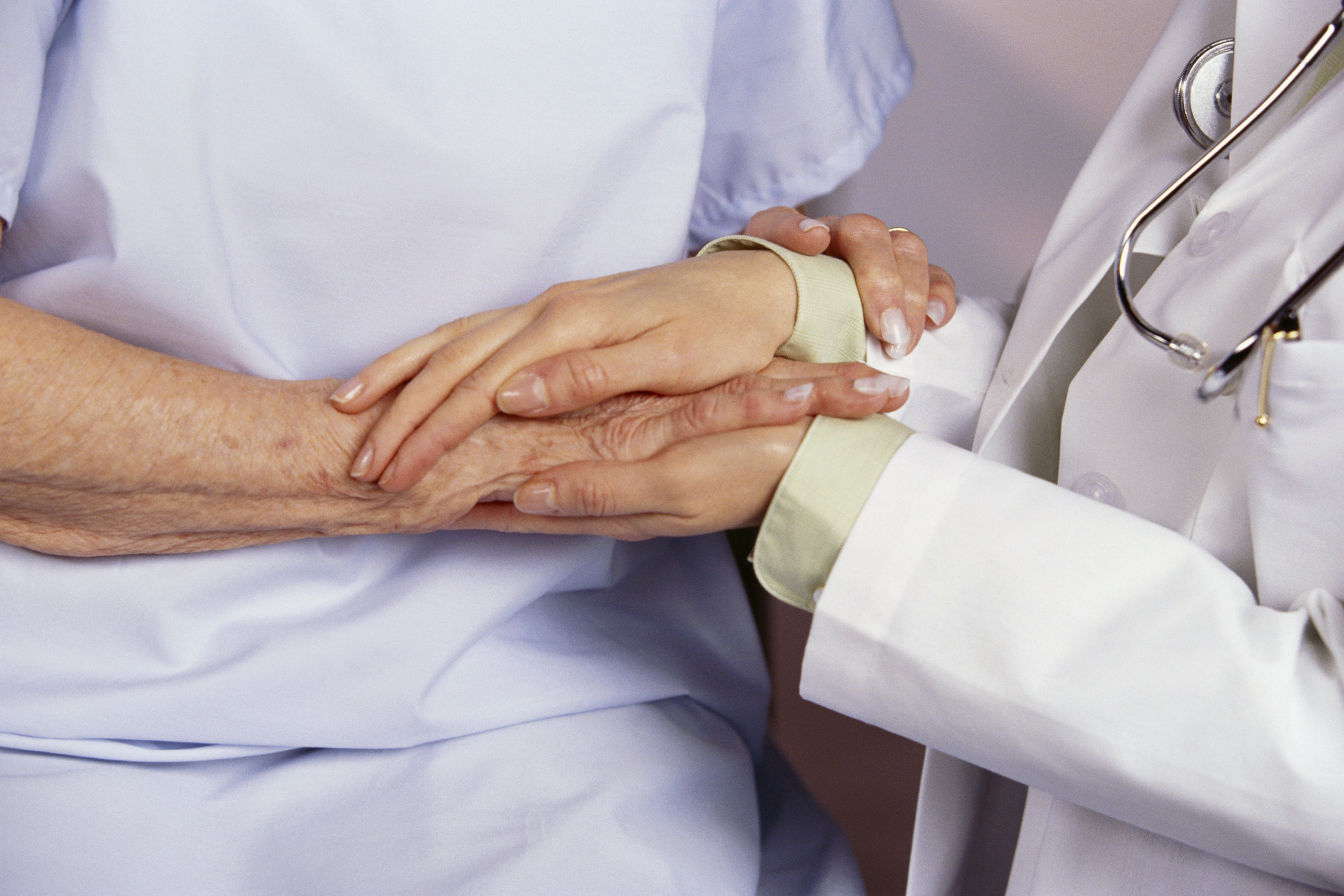 A doctor holding hands with a patient. | Source: Getty Images