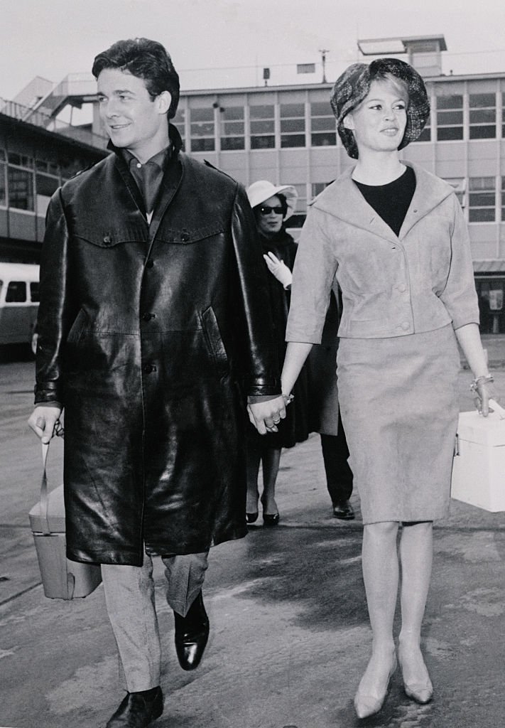 Main dans la main, l'actrice française Brigitte Bardot et son mari, l'acteur Jacques Charrier, arrivent à l'aéroport d'Orly pour prendre l'avion pour Lisbonne, Portugal. Le 27 mars. | Photo : Getty Images