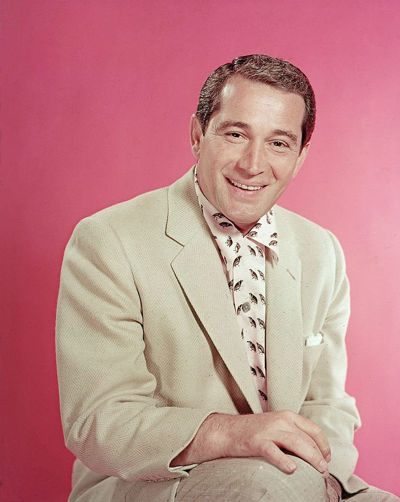  Perry Como (1912 - 2001) as he sits in a pink and black shirt under a light tan jacket, mid 1950s. | Getty Images
