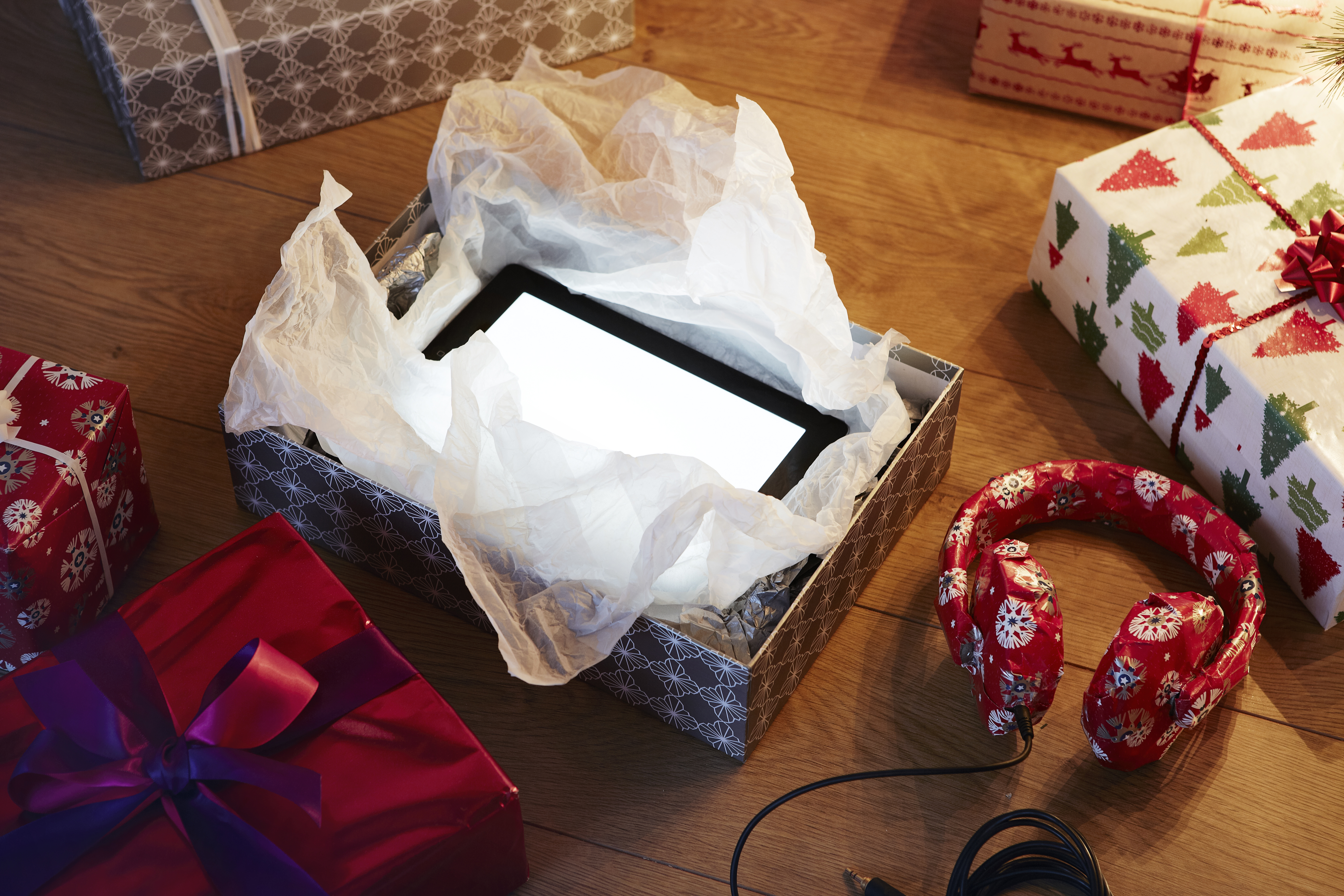 An unwrapped Christmas present revealing a tablet computer | Source: Getty Images