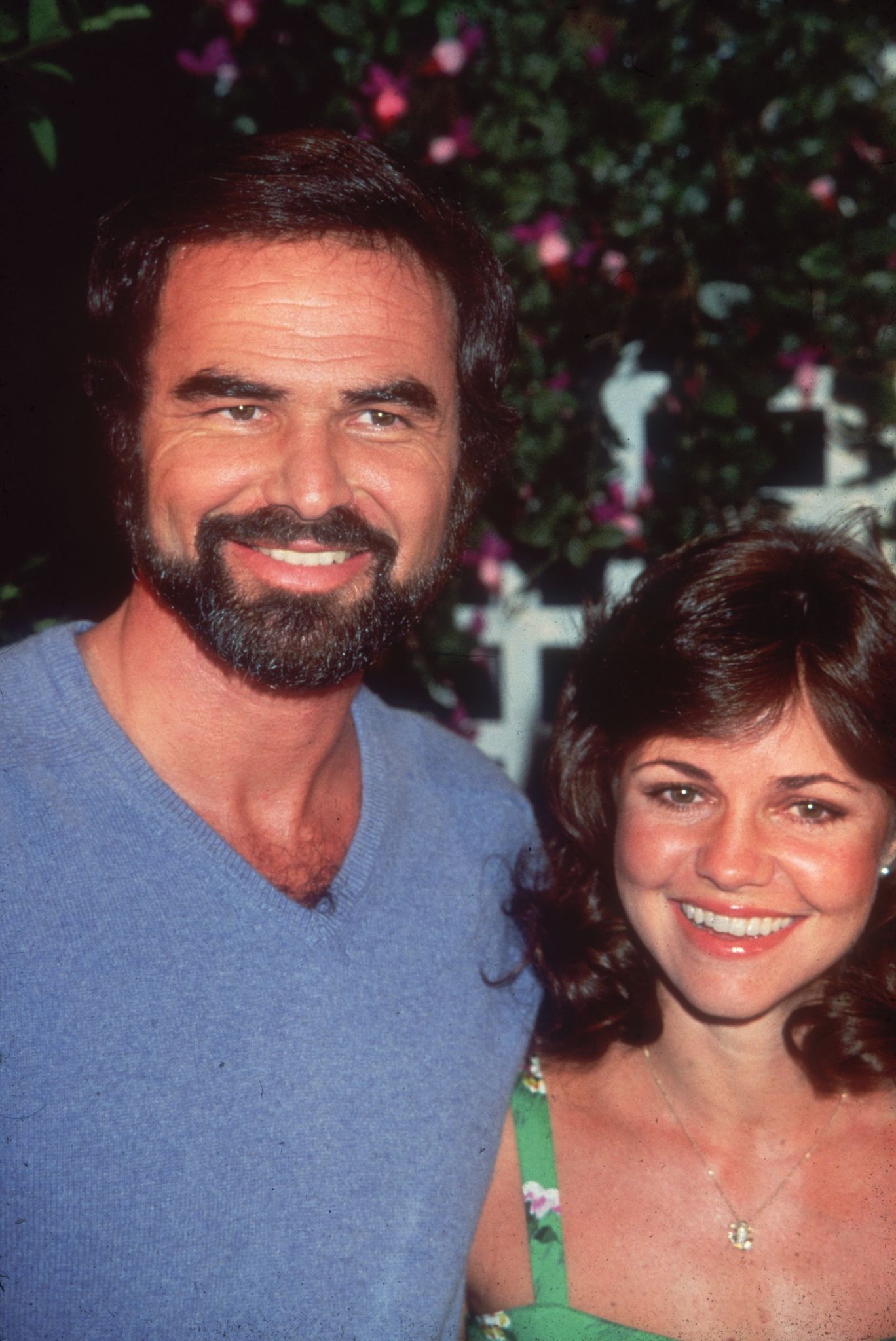 American actor Burt Reynolds smiles with actress Sally Field, while attending an outdoor event on August 1977. | Photo: Getty Images