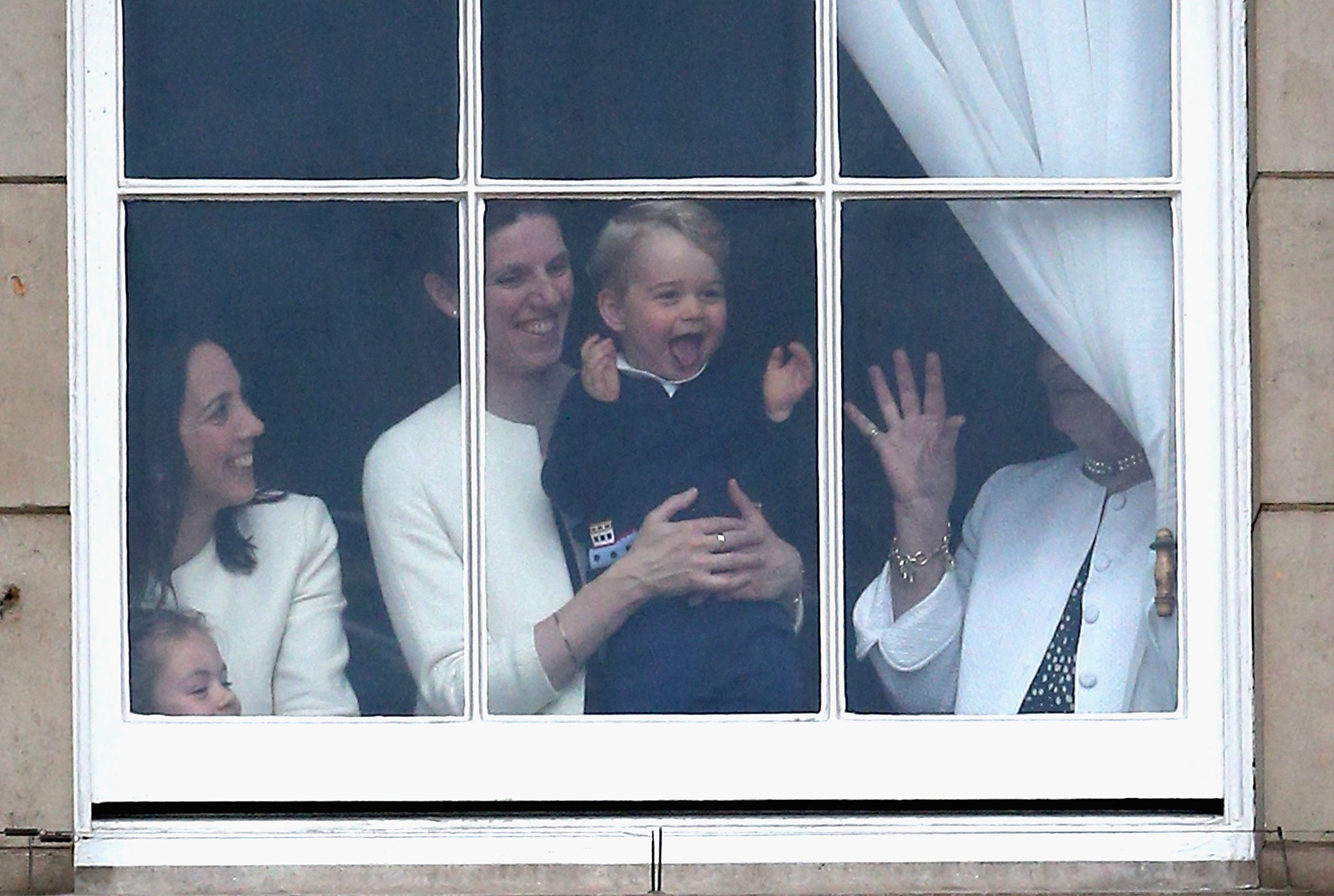 Prince George of Cambridge is held by his nanny Maria Teresa Turrion Borrallo as he waves from the window of Buckingham Palace as he watches the Trooping the Colour on June 13, 2015, in London, England. | Source: Getty Images.