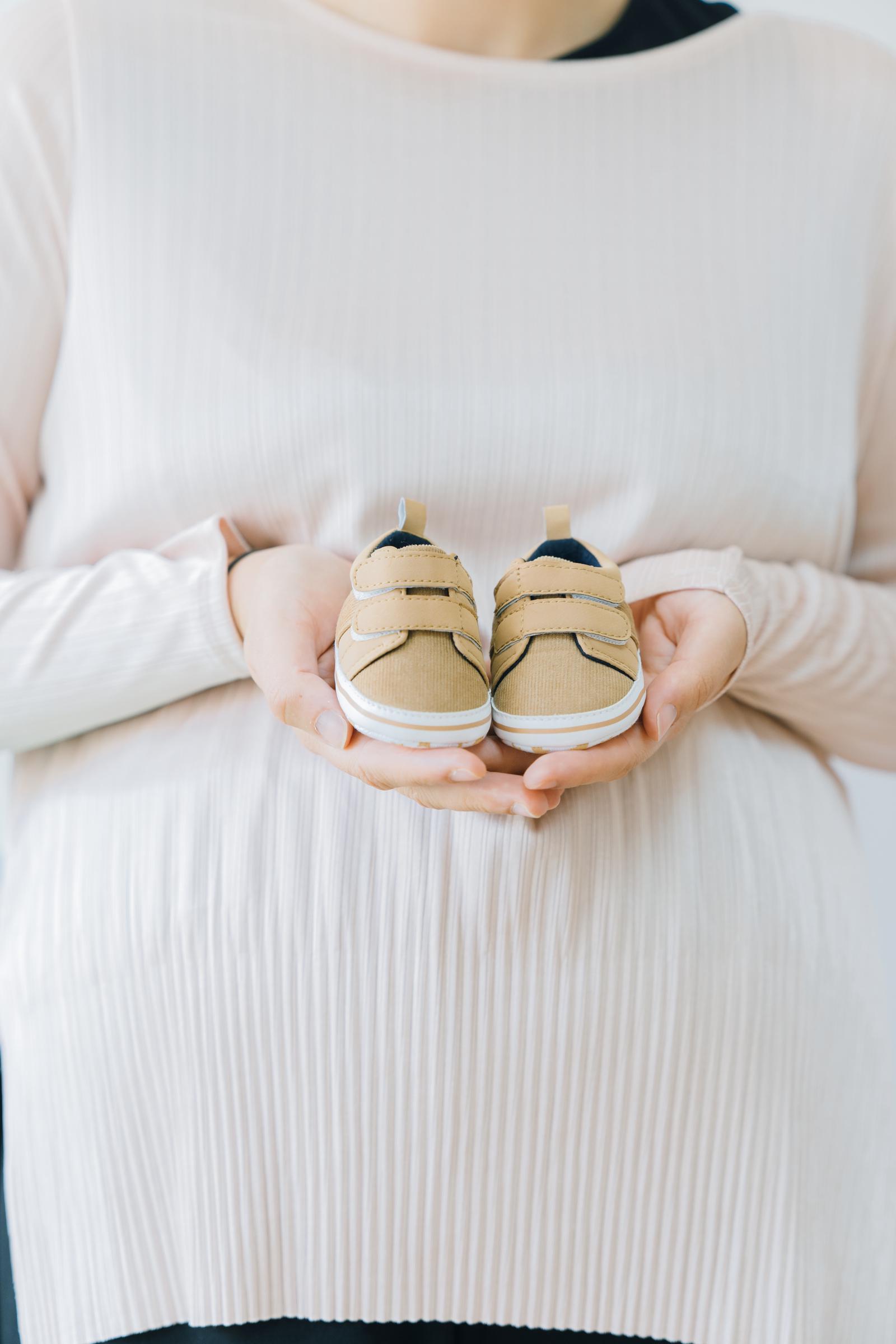 Uma mulher segurando pequenos sapatos de bebê | Fonte: Freepik