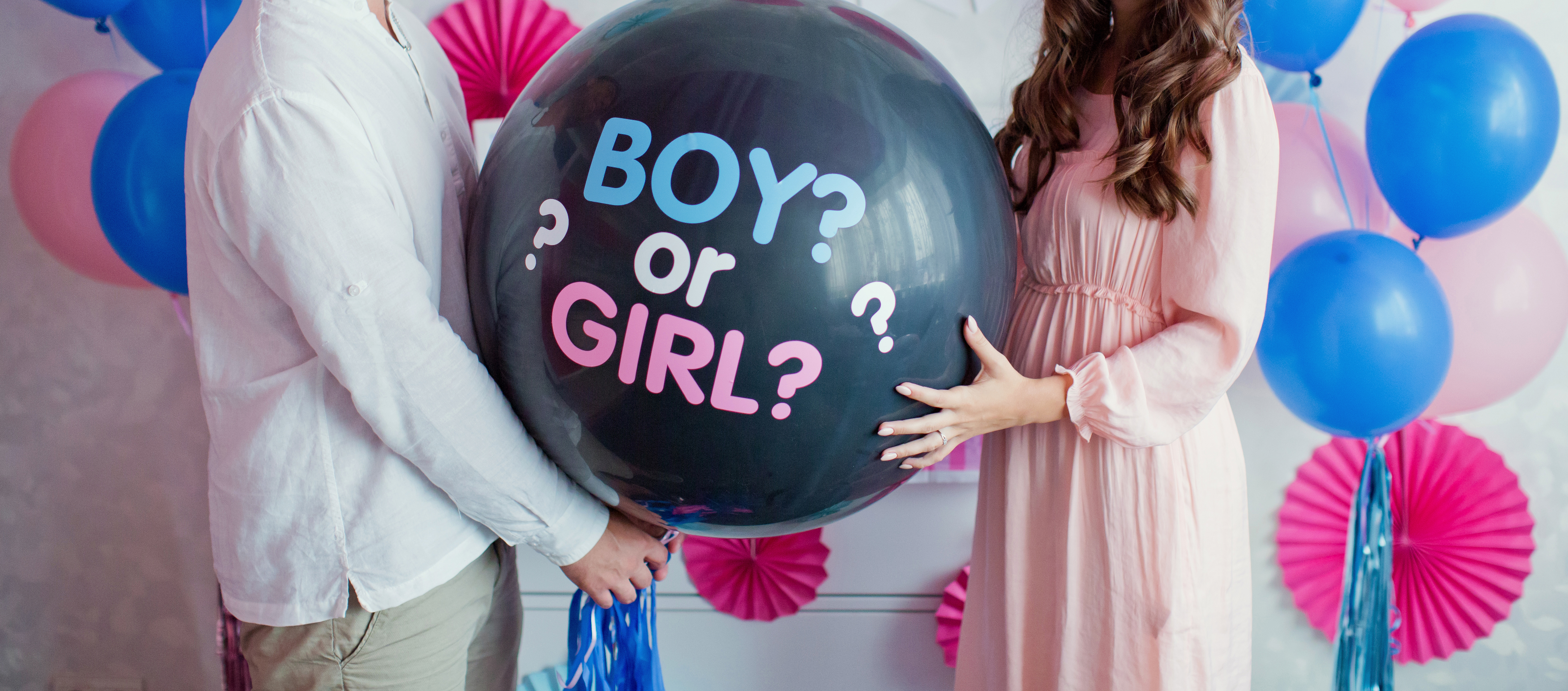 Man and woman holding a black balloon with "boy or girl?" during a gender reveal party | Source: Shutterstock