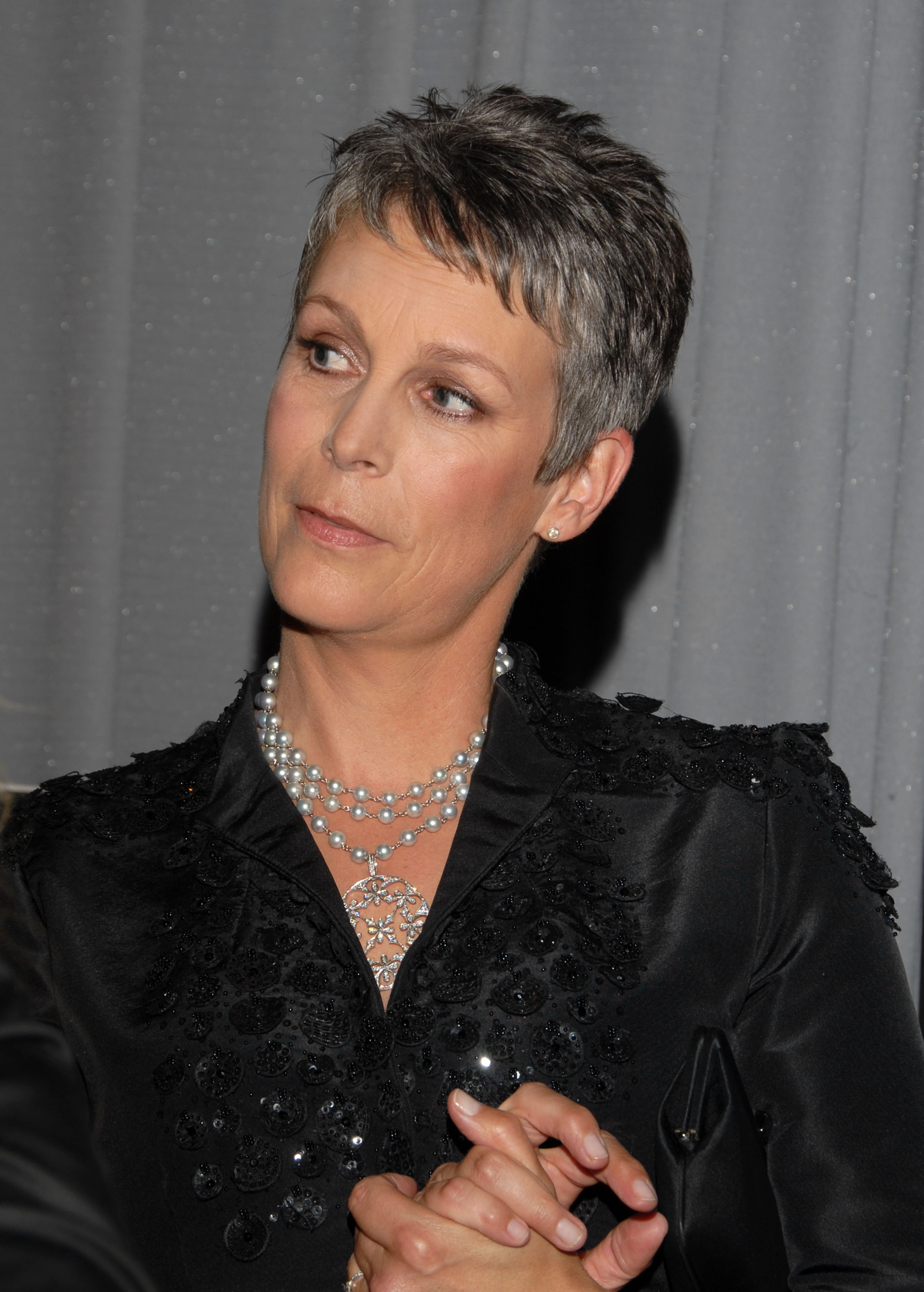 Jamie Lee Curtis exudes elegance backstage at the 2006 Screen Actors Guild Talent Retreat, wearing a beaded black blouse with layered pearl necklaces and a jeweled pendant, her silver pixie cut completing the sophisticated look.
