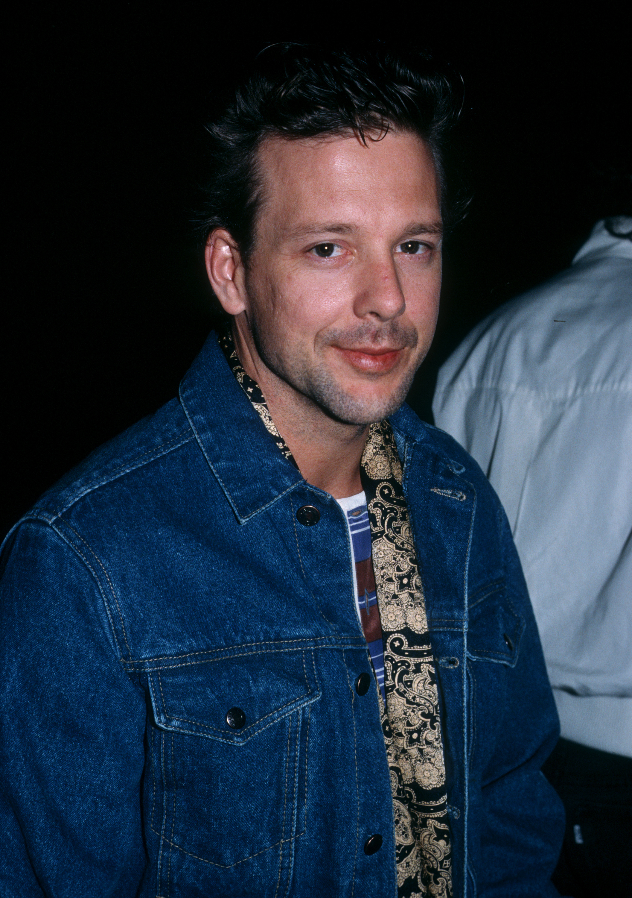 Photographed at Spago Restaurant in West Hollywood, California, on September 15, 1984, Mickey Rourke wore a denim jacket over a patterned scarf and striped shirt as he looked toward the camera. By this point in the decade, the actor's career was well underway, with his dark swept-back hair and lightly stubbled features becoming increasingly familiar to movie audiences.