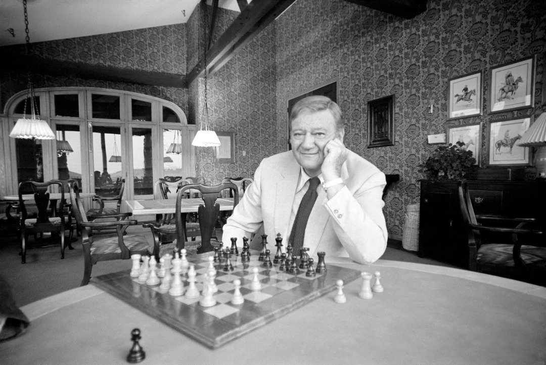 American actor John Wayne who recently starred in 'Brannigan' at home in Texas playing a game of chess. | Source: Getty Images