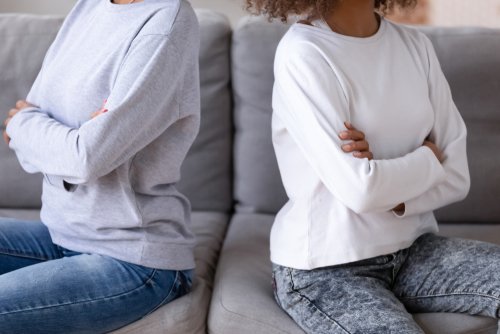 A close up of two women sitting with their backs to each other. | Source: Shutterstock.