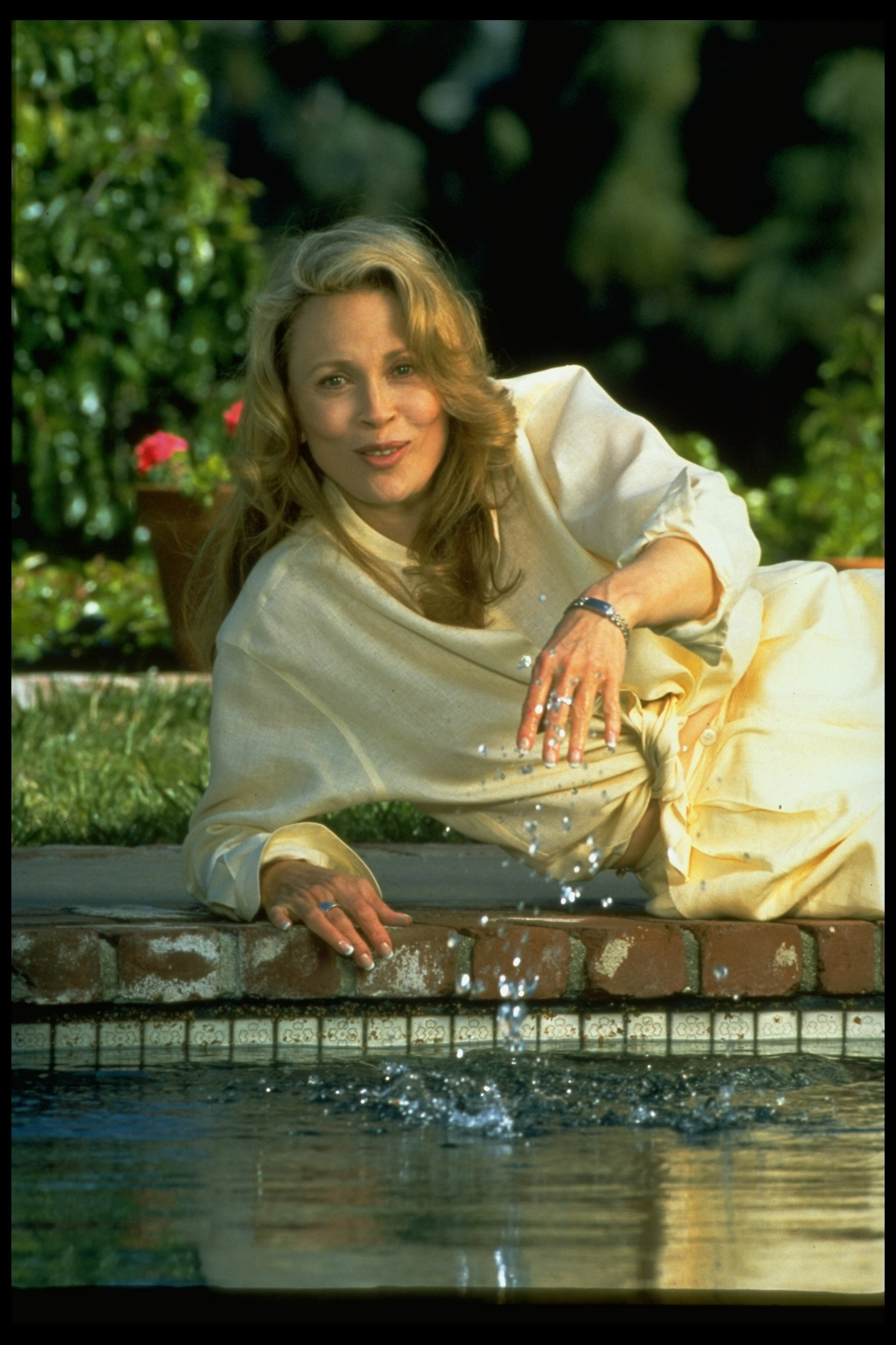 Faye Dunaway lying on her side at edge of pool at her Hollywood home in 1995 | Source: Getty Images