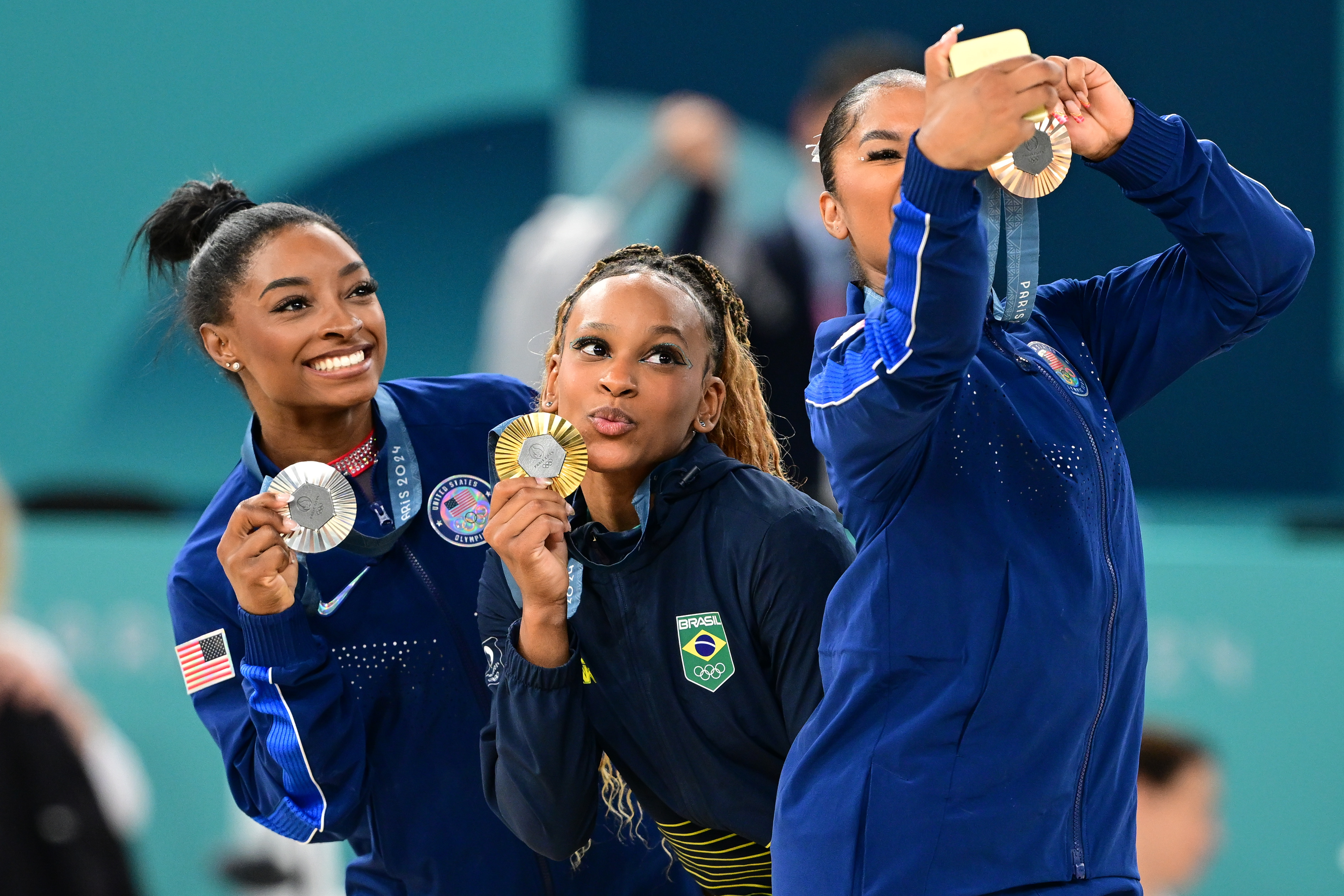 Simone Biles (silver), Brazil's Rebeca Andrade (gold) and US' Jordan Chiles (bronze) pose for a selfie during the podium ceremony for the artistic gymnastics women's floor exercise event of the Paris 2024 Olympic Games at the Bercy Arena in Paris, on August 5, 2024 | Source: Getty Images