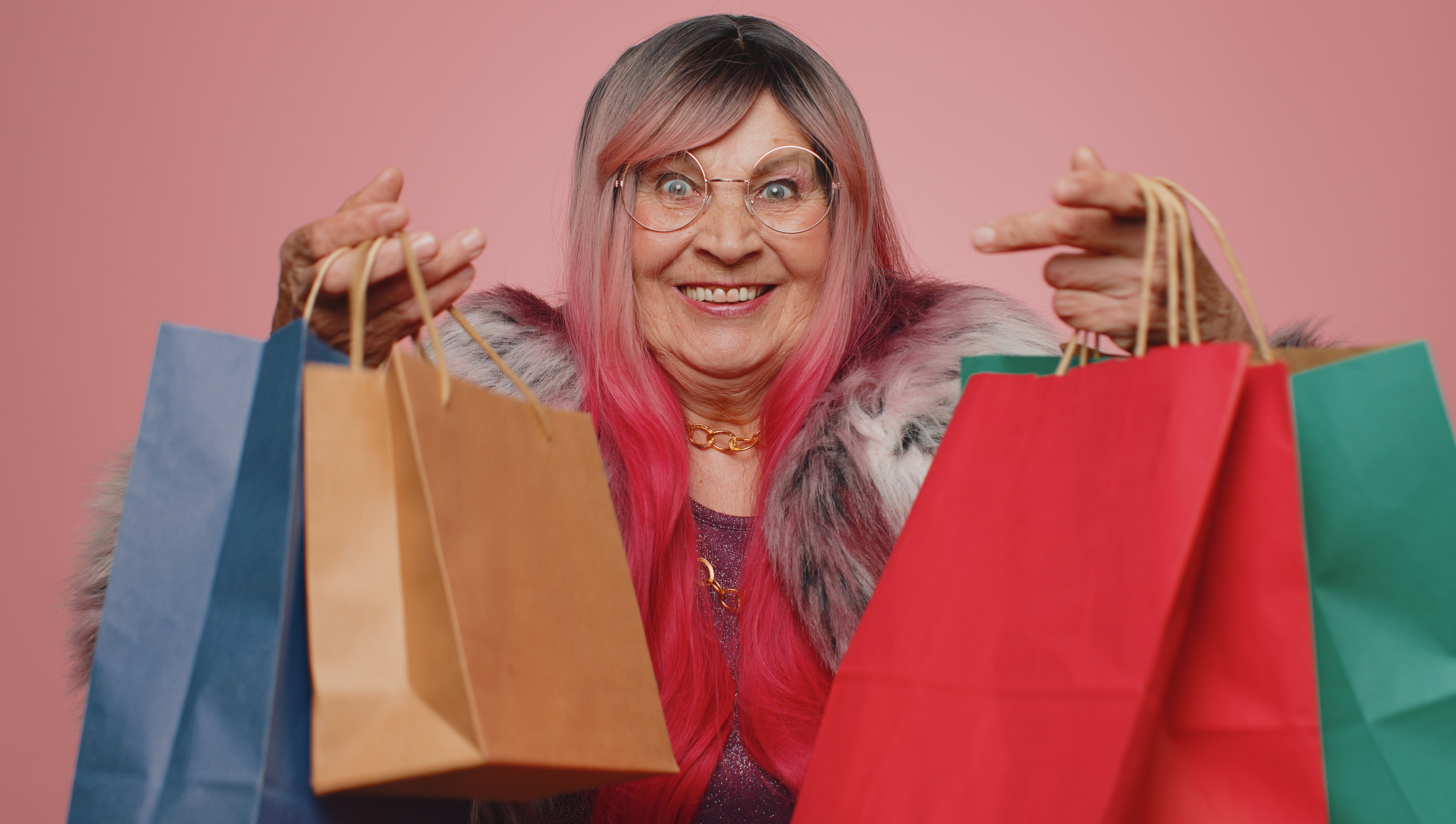 An elderly woman smiling while holding shopping bags | Source: Shutterstock