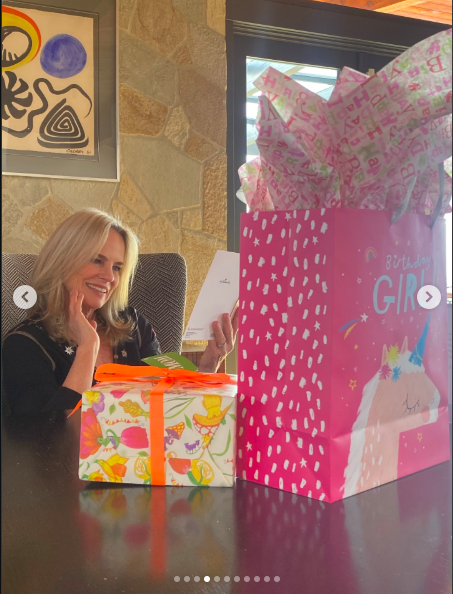 Jennifer Runyon reading a birthday card while seated next to gifts, posted on March 8, 2026. | Source: Instagram/bayleycorman