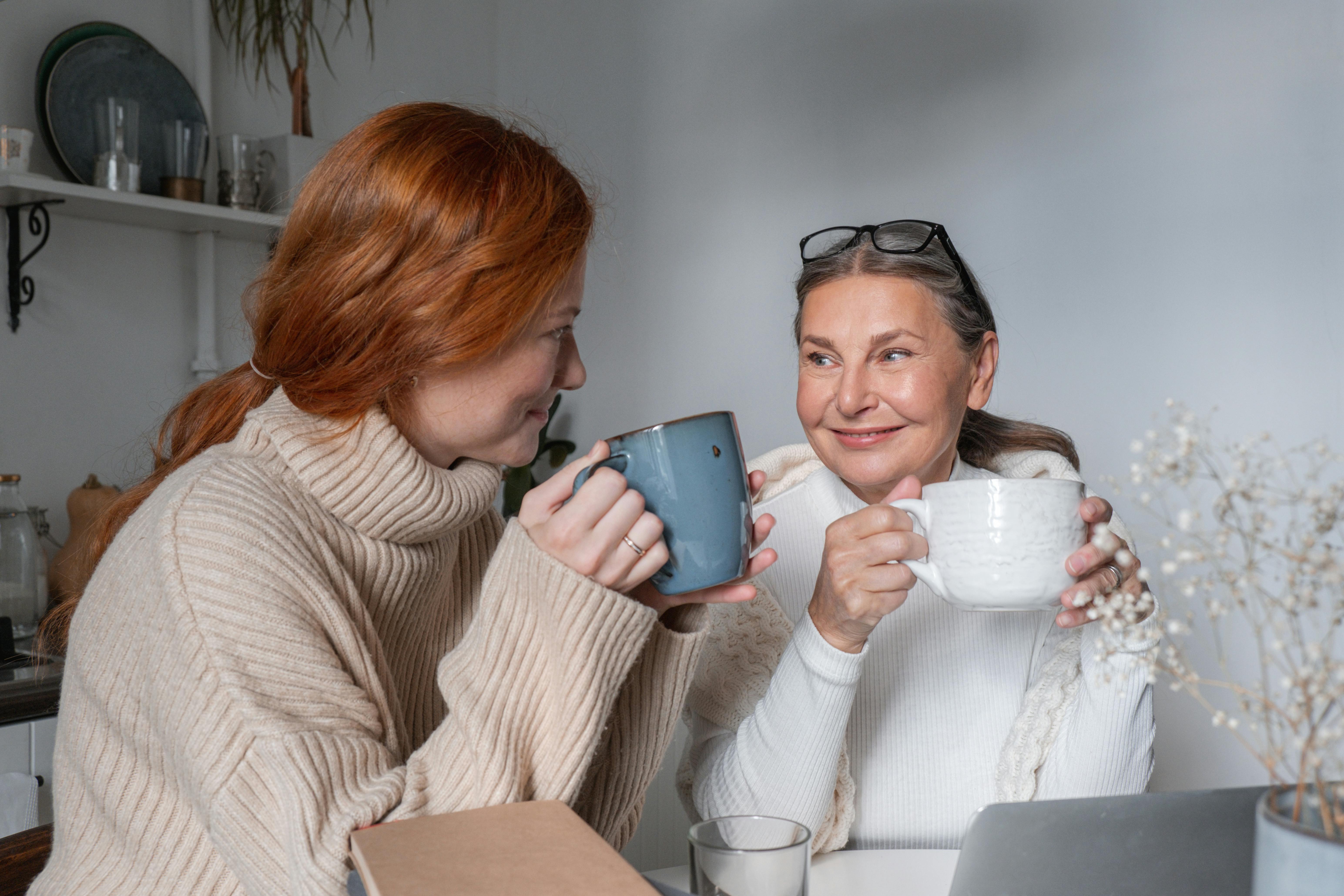 An older woman and a younger one smiling while having a beverage together | Source: Pexels