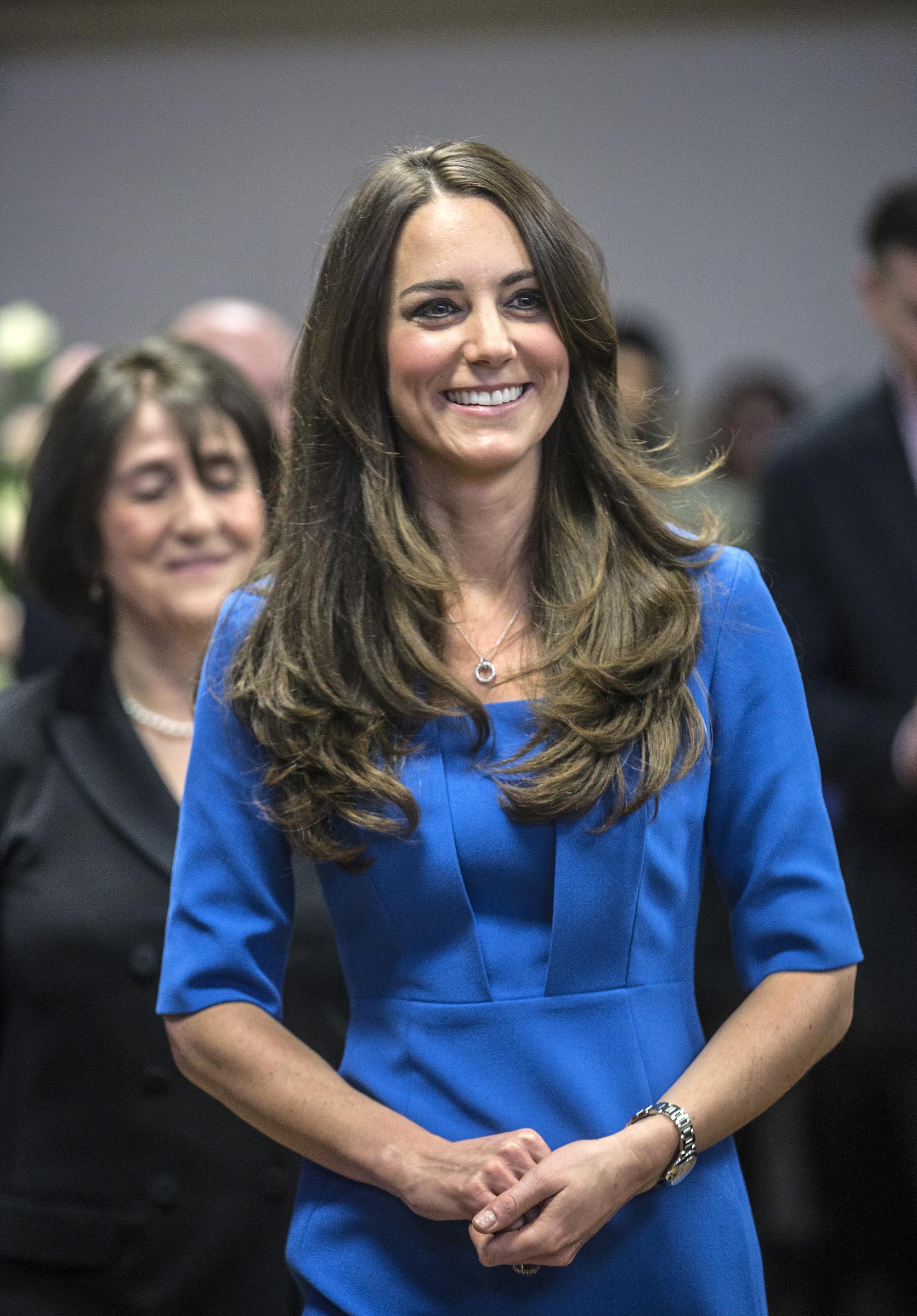 Catherine, Duchess of Cambridge, visits Northolt High School for the opening of the ICAP Art Room. Wearing a blue outfit, she smiled warmly as she spoke with students and staff, her hair styled in soft, loose waves.