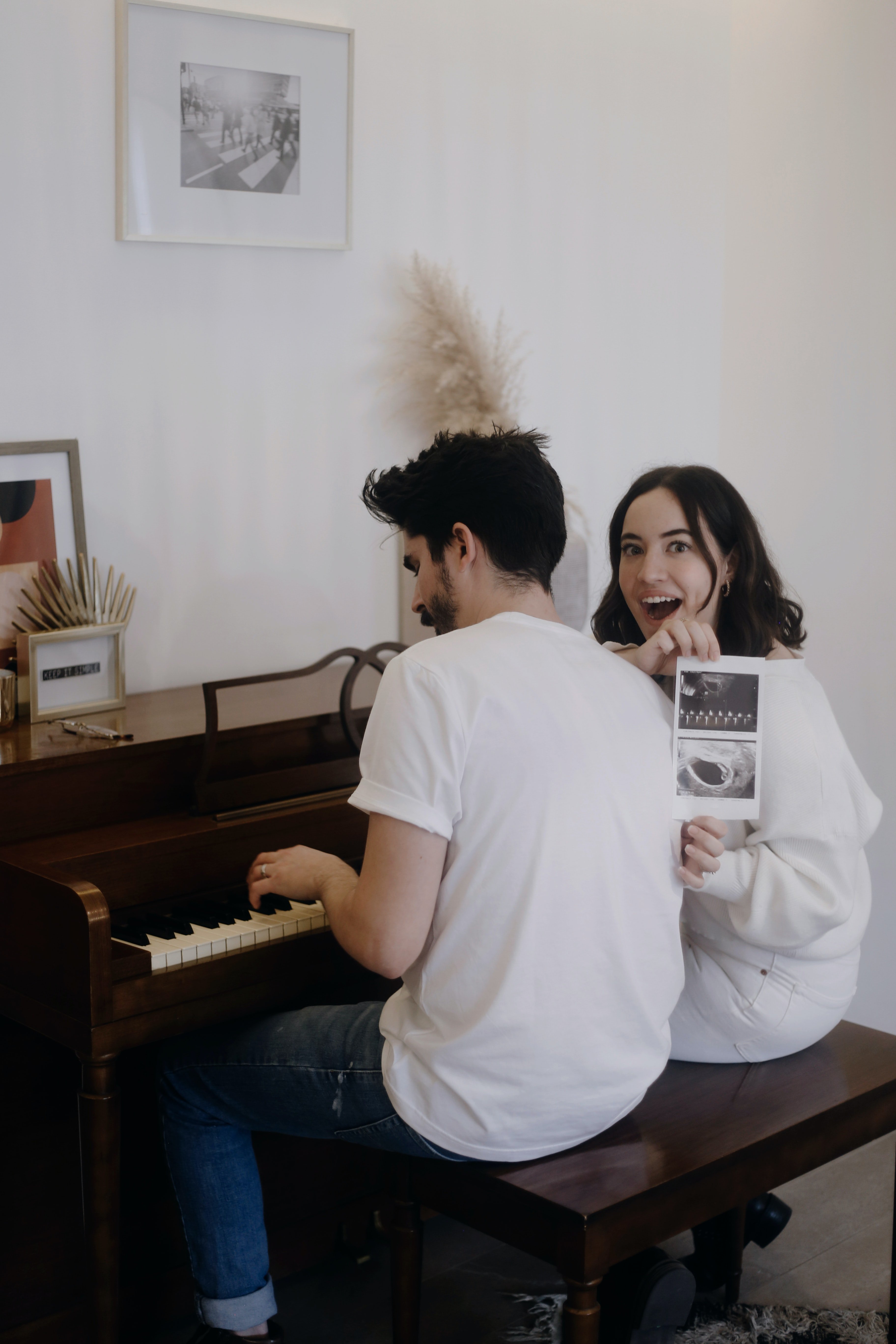 Wife flaunts an ultrasound picture of her baby while her husband plays the piano | Photo: Unsplash/jonathansancheziam