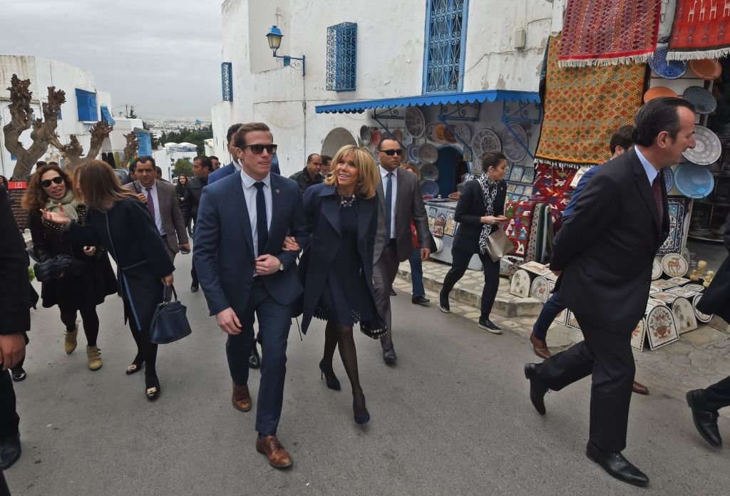 Brigitte Macron est escortée par un membre de sa garde rapprochée lors d'une visite dans la ville de Sidi Bou Said, près de Tunis, le 1er février 2018. | Photo : Getty Images