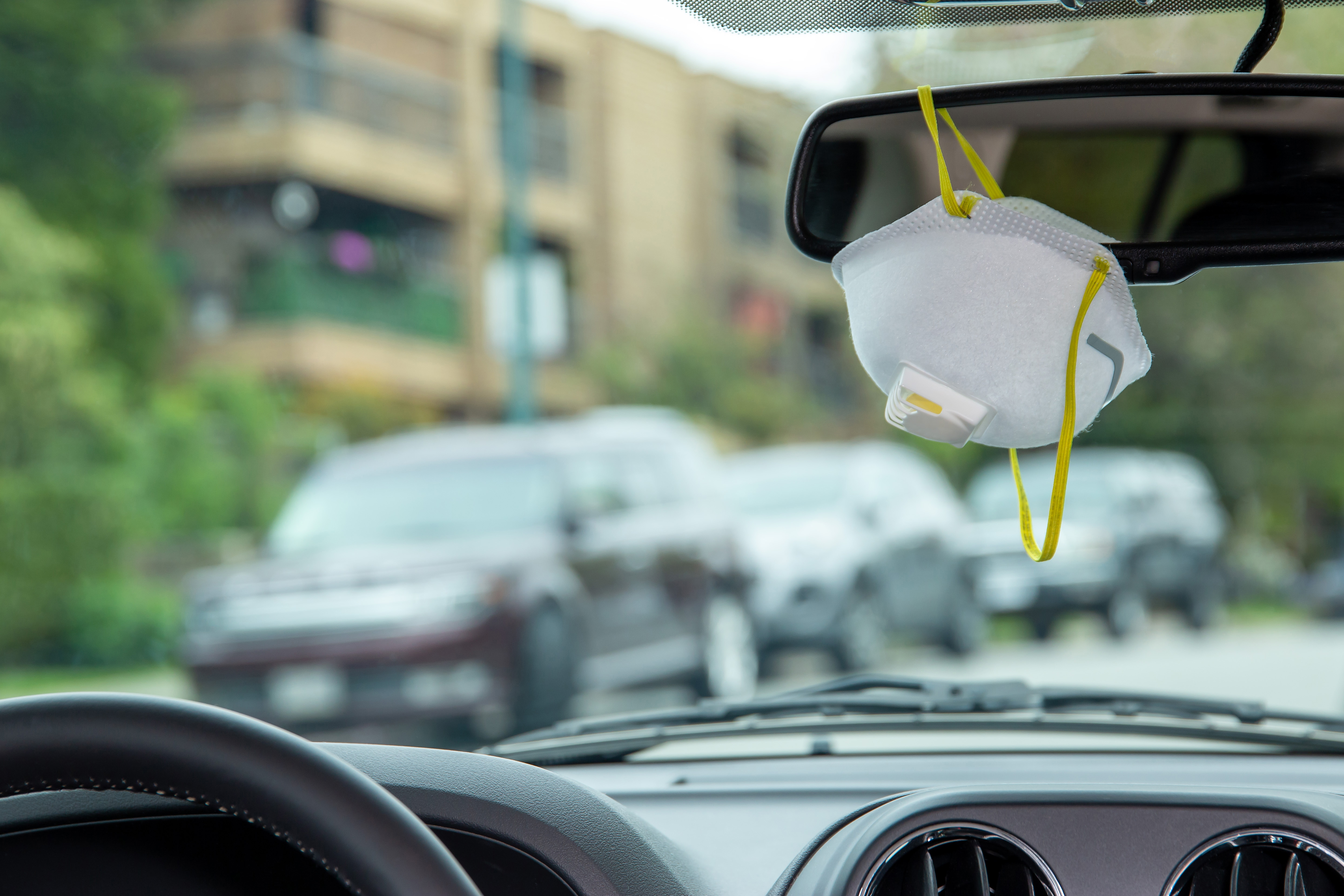 A protective mask is hanging on the rearview mirror of a car | Source: Getty Images
