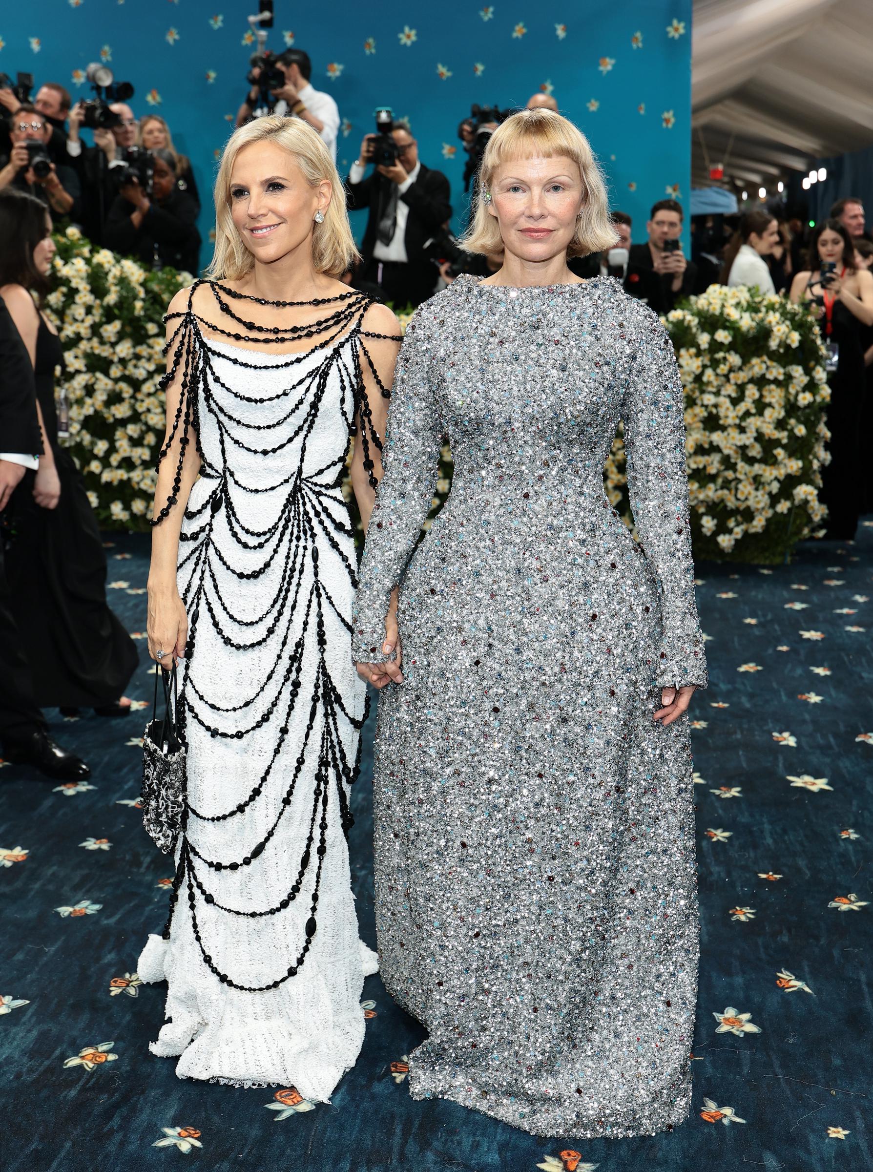 Designer Tory Burch and Pamela Anderson are seen hand in hand on the Met Gala carpet. The two appeared together in tribute to the custom gown Anderson wore — a showpiece created in Burch's atelier for the "Superfine: Tailoring Black Style" celebration.