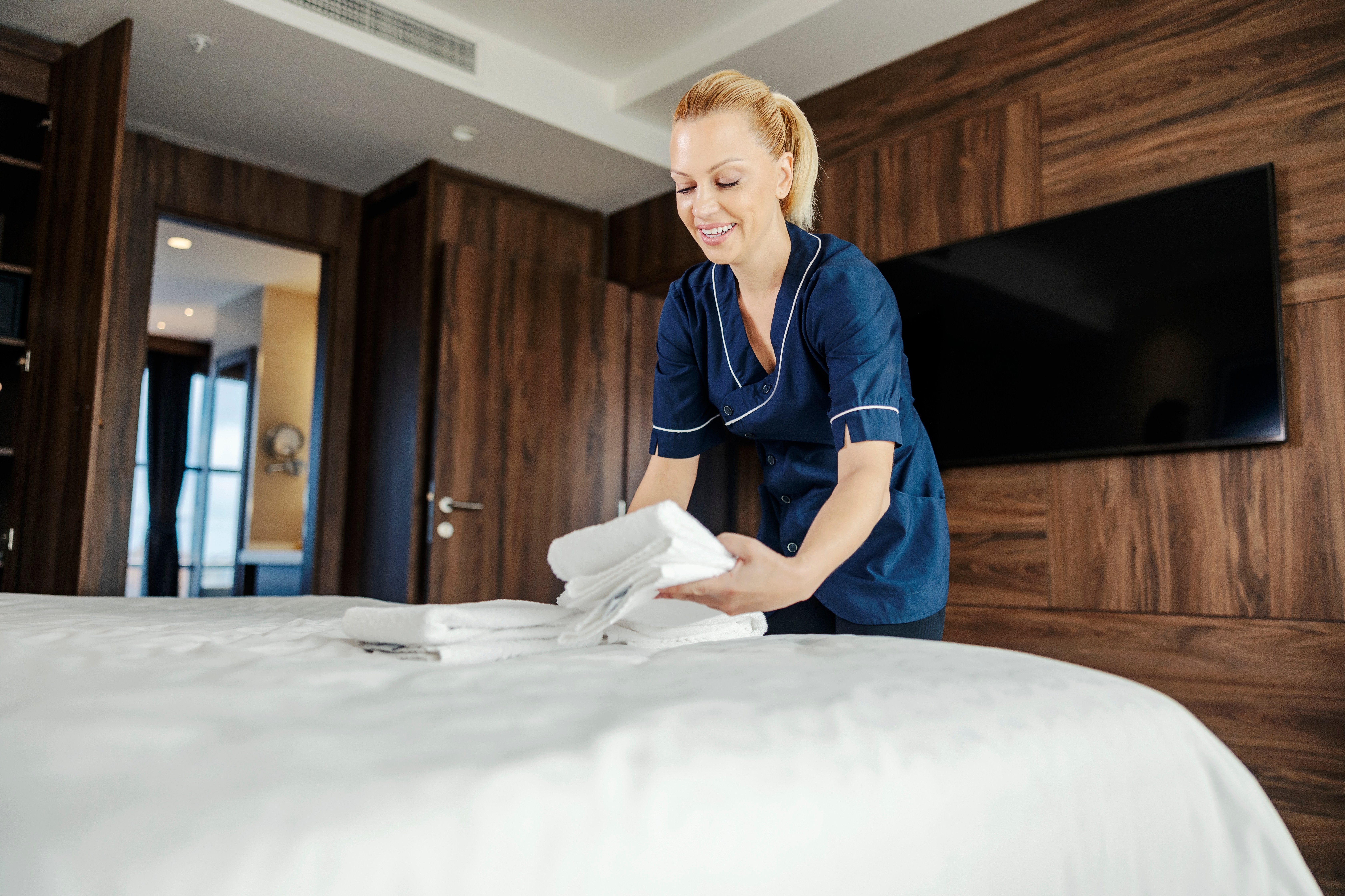 A female staff worker putting clean towels on a bed in a hotel room | Source: Shutterstock