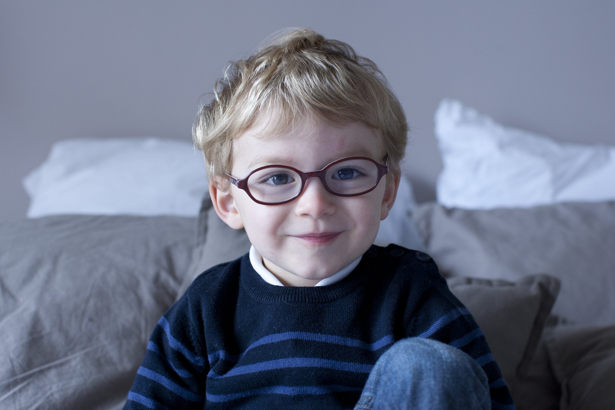 A little boy sitting on the bed smiling. | Photo: Getty Images