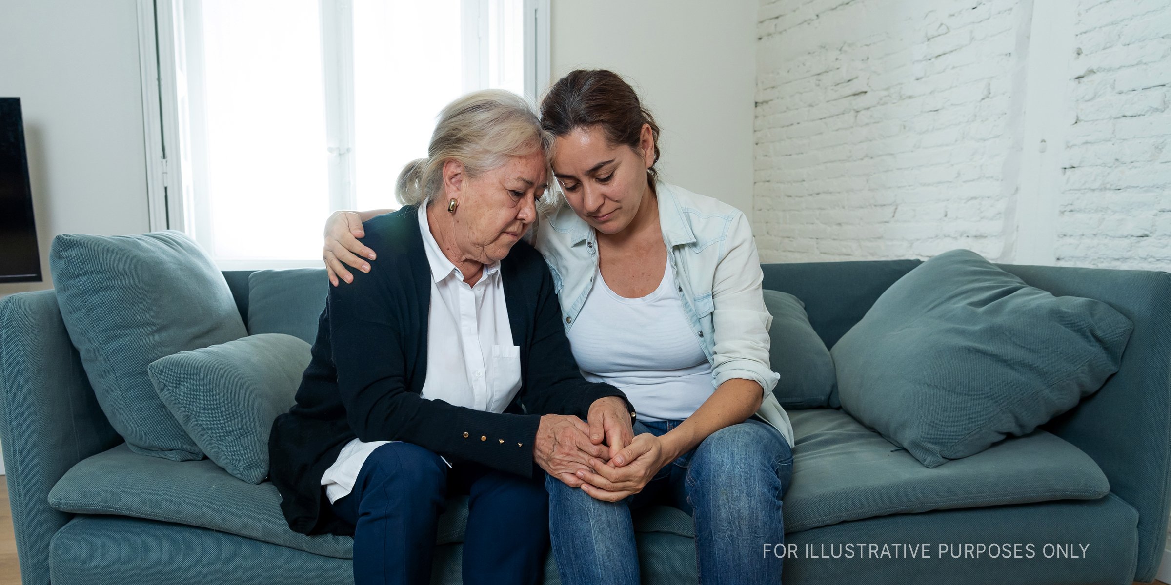 Old woman and younger woman holding each other on a sofa. | Source: Shutterstock