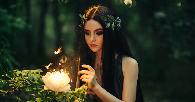 A fairy in a forest with a magical flower. | Photo: Shutterstock