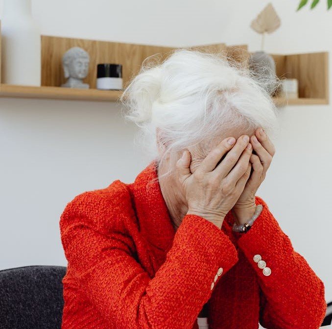 Mujer mayor tapando su rostro con sus manos. | Foto: Pexels