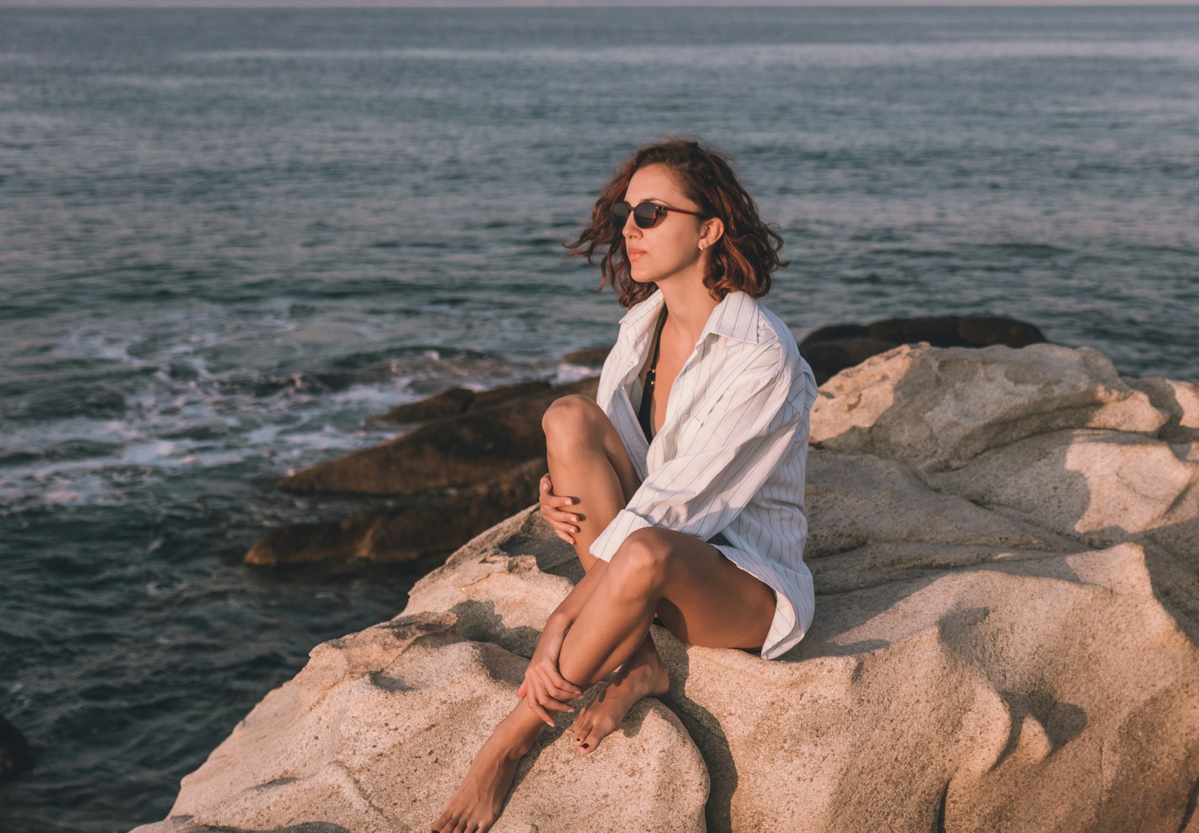 A woman sitting on beach rocks | Source: Unsplash